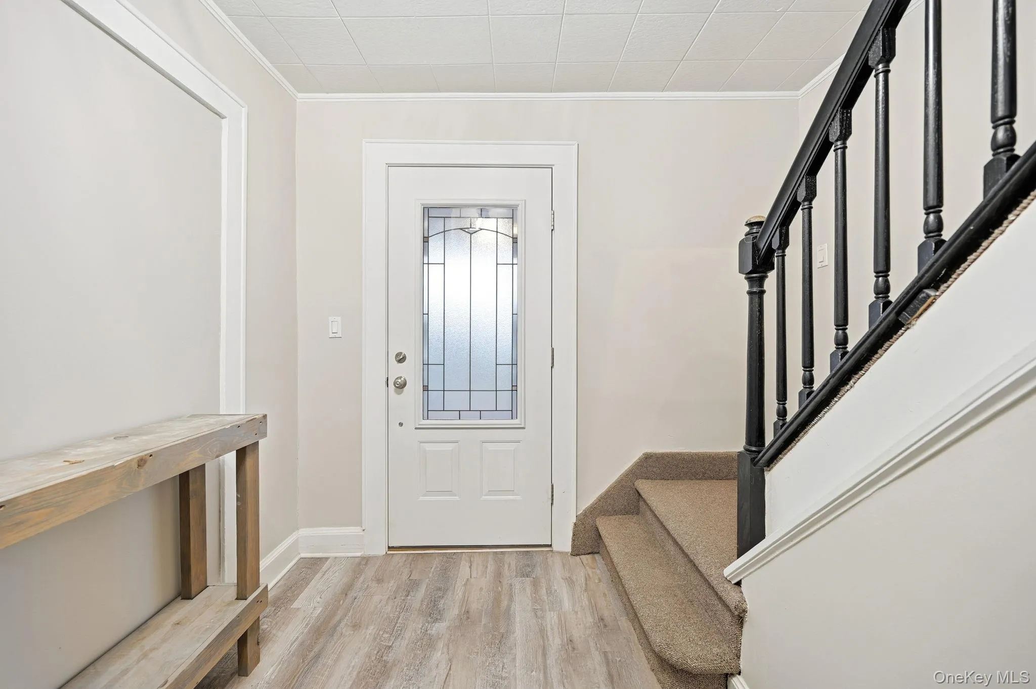 Entrance foyer with stairway, light wood finished floors, and crown molding Entrance foyer with stairway, light wood finished floors, and crown molding
