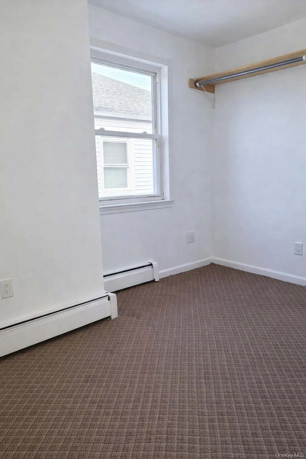 Unfurnished room featuring a baseboard heating unit and dark carpet Unfurnished room featuring a baseboard heating unit and dark carpet