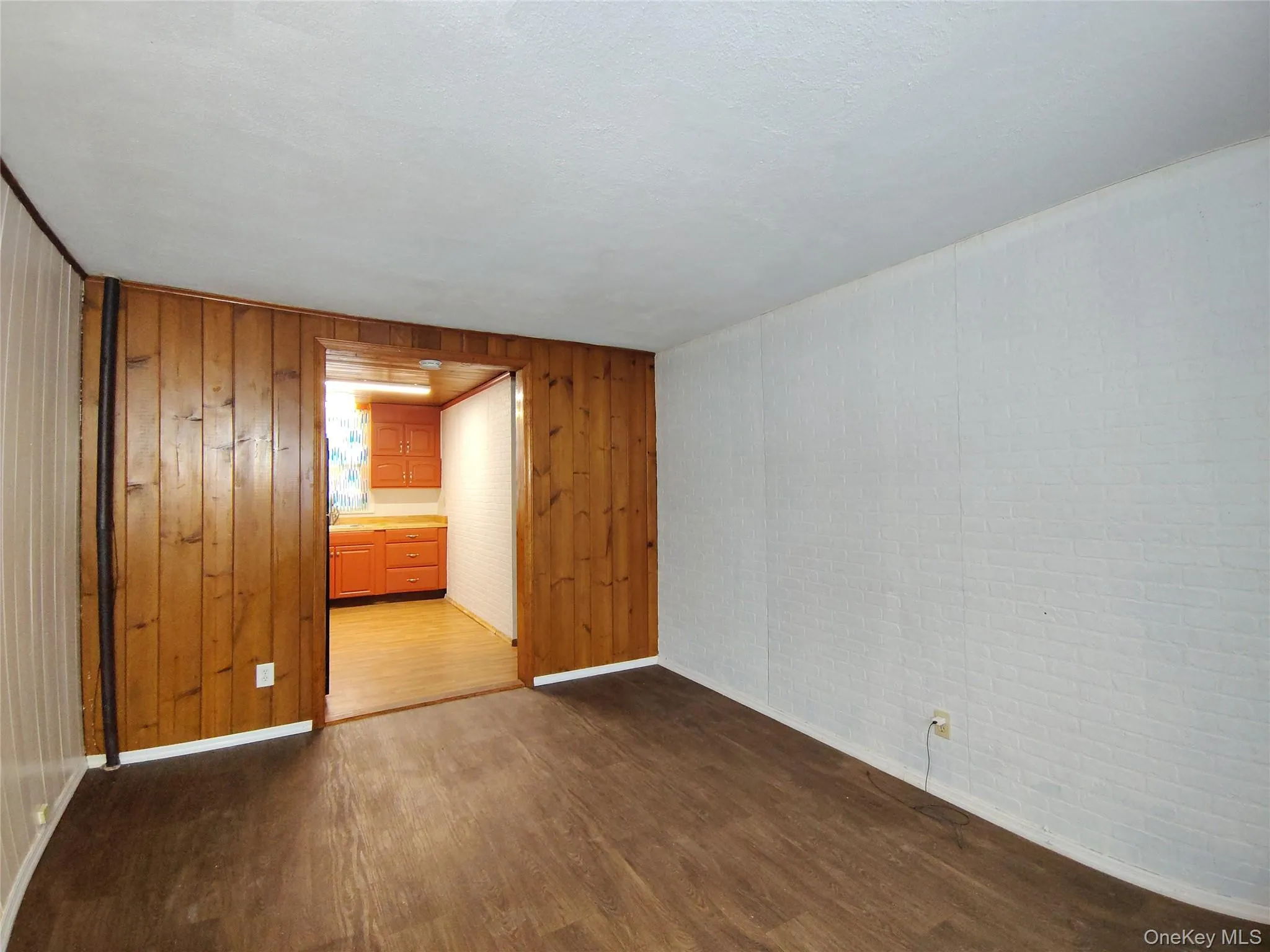 Unfurnished room with dark wood-type flooring and wood walls Unfurnished room with dark wood-type flooring and wood walls