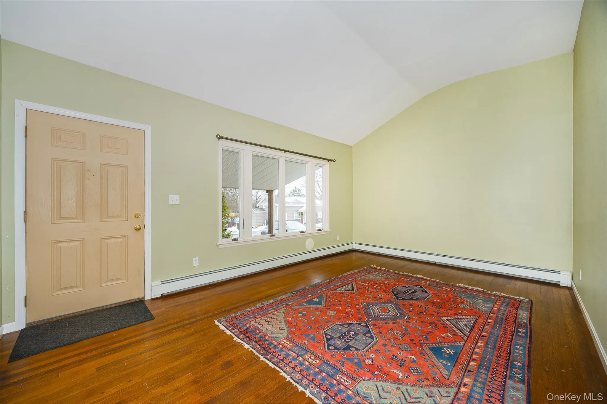 Foyer entrance featuring hardwood / wood-style floors, a baseboard radiator, and vaulted ceiling Foyer entrance featuring hardwood / wood-style floors, a baseboard radiator, and vaulted ceiling