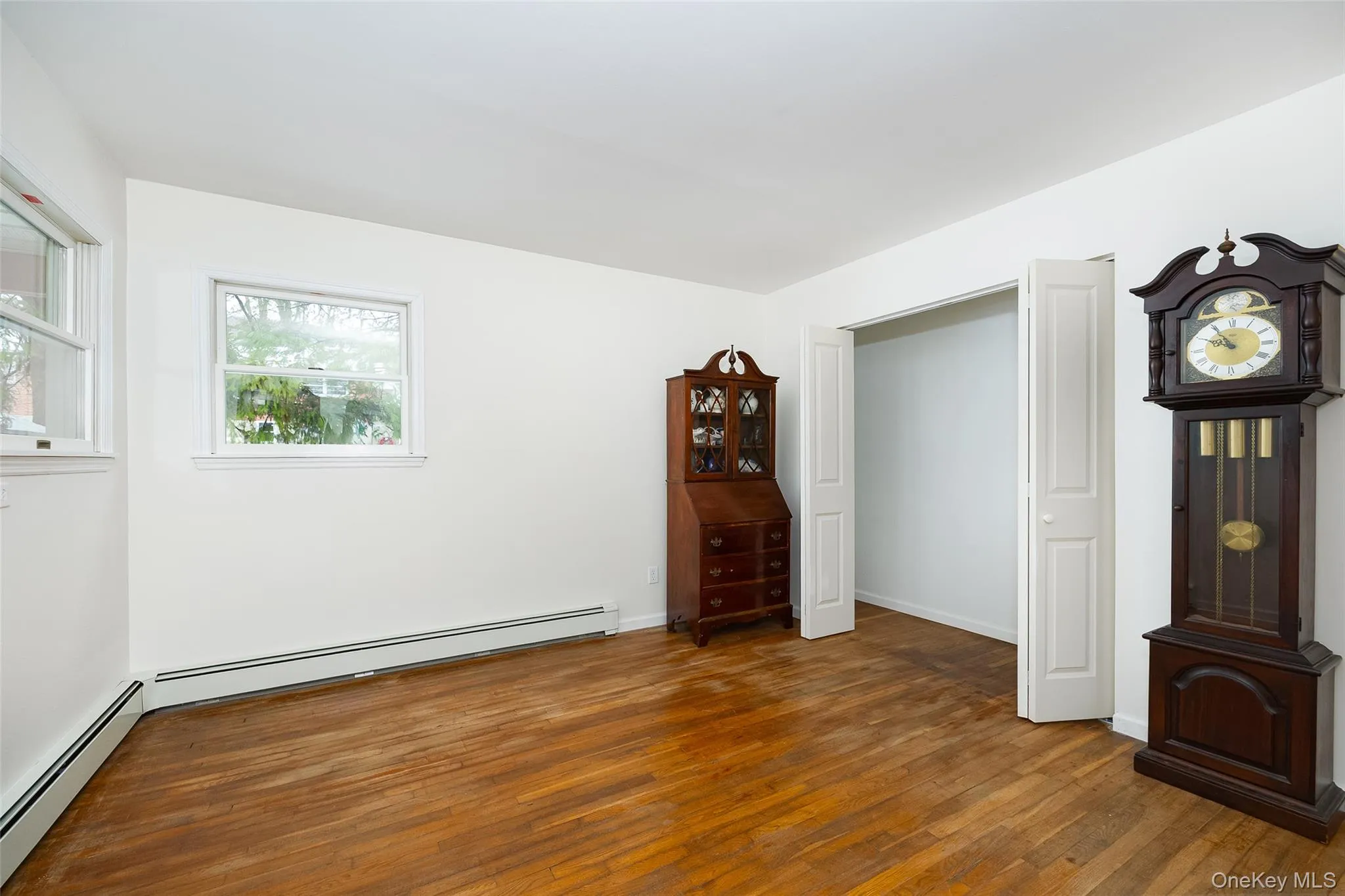 Unfurnished bedroom featuring wood-type flooring and baseboard heating Unfurnished bedroom featuring wood-type flooring and baseboard heating