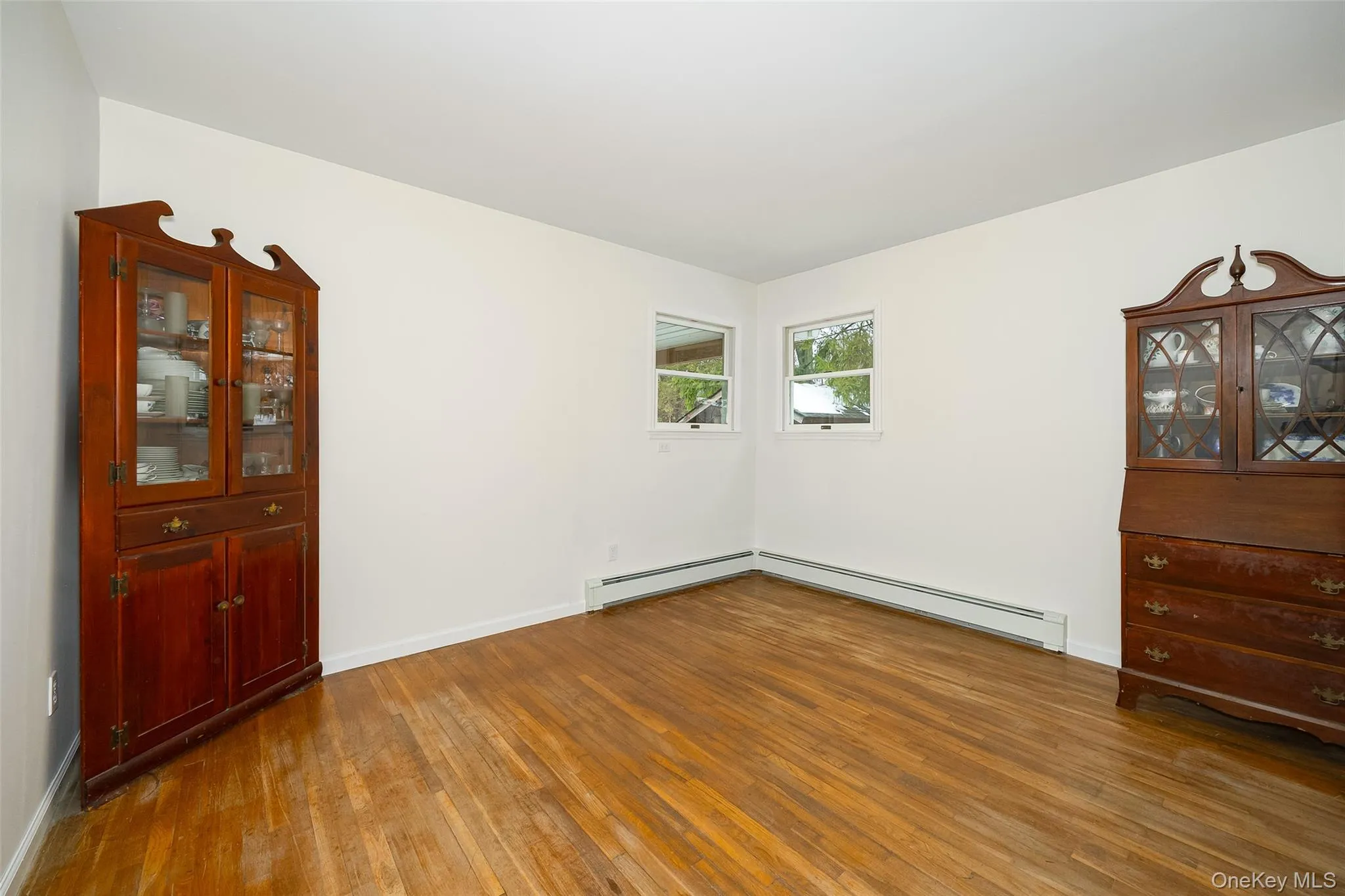 Empty room with hardwood / wood-style flooring and a baseboard heating unit Empty room with hardwood / wood-style flooring and a baseboard heating unit