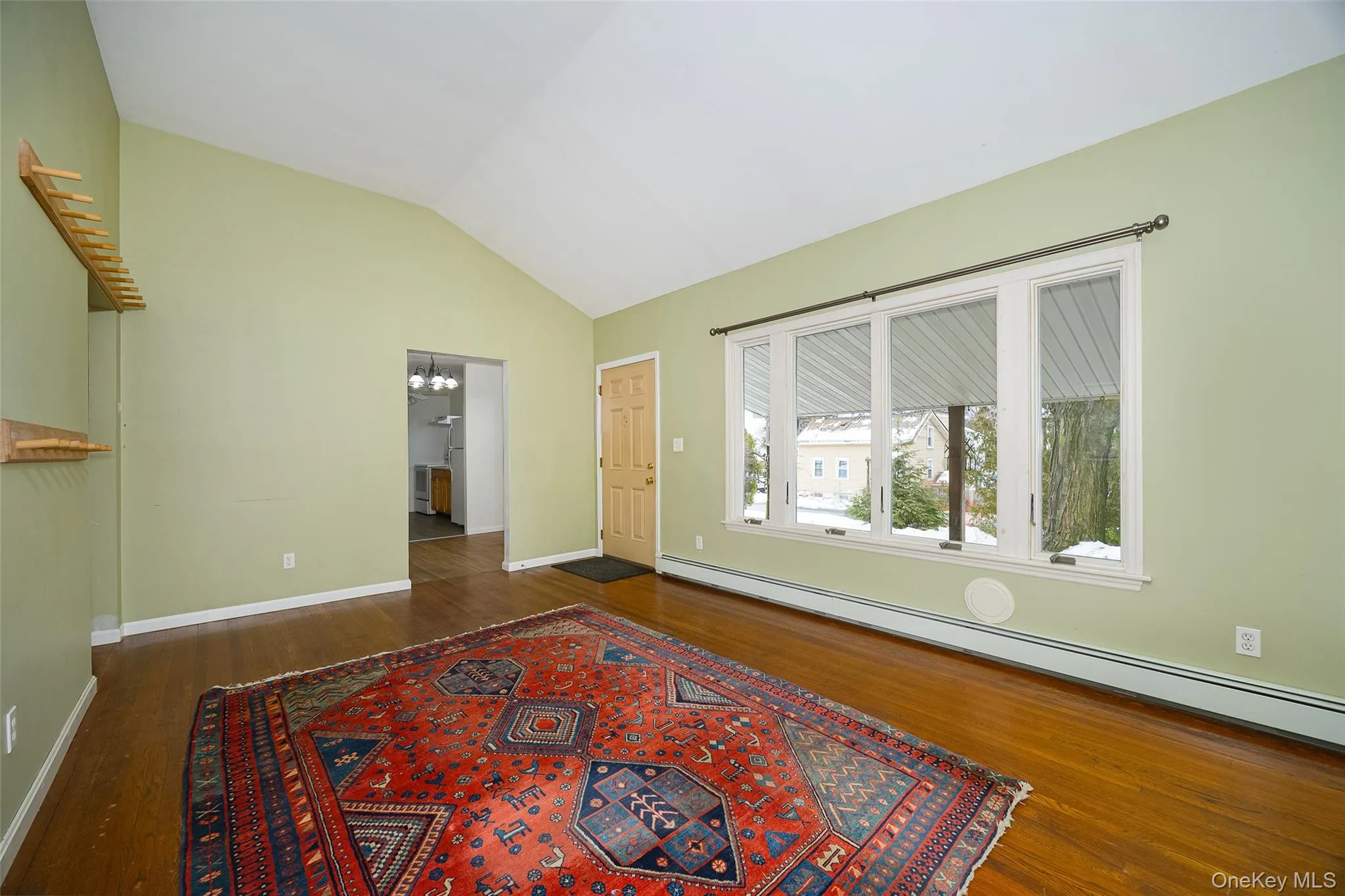 Unfurnished room featuring a chandelier, a baseboard radiator, vaulted ceiling, and dark wood-type flooring Unfurnished room featuring a chandelier, a baseboard radiator, vaulted ceiling, and dark wood-type flooring