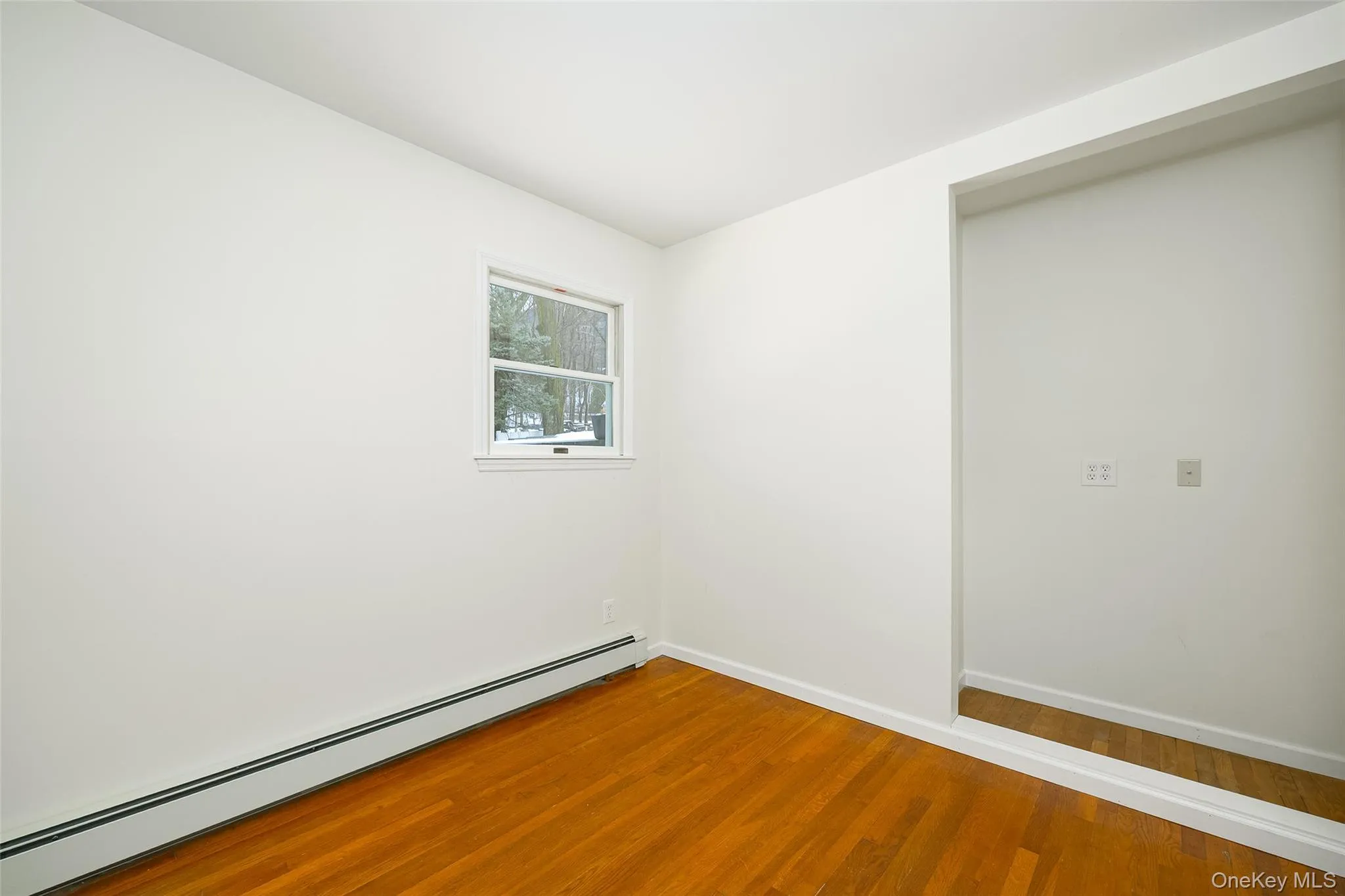 Empty room with a baseboard radiator and wood finished floors Empty room with a baseboard radiator and wood finished floors