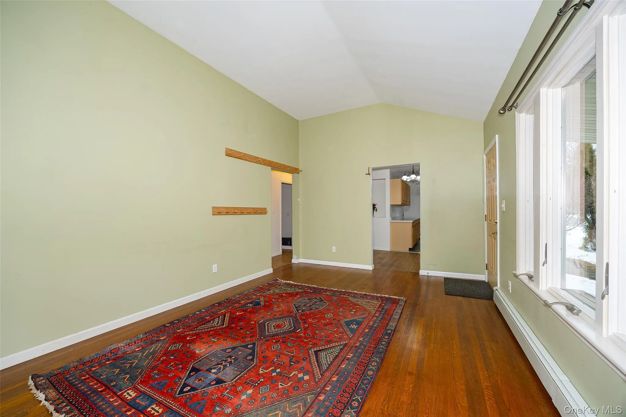 Empty room with lofted ceiling, a baseboard radiator, and dark wood finished floors Empty room with lofted ceiling, a baseboard radiator, and dark wood finished floors