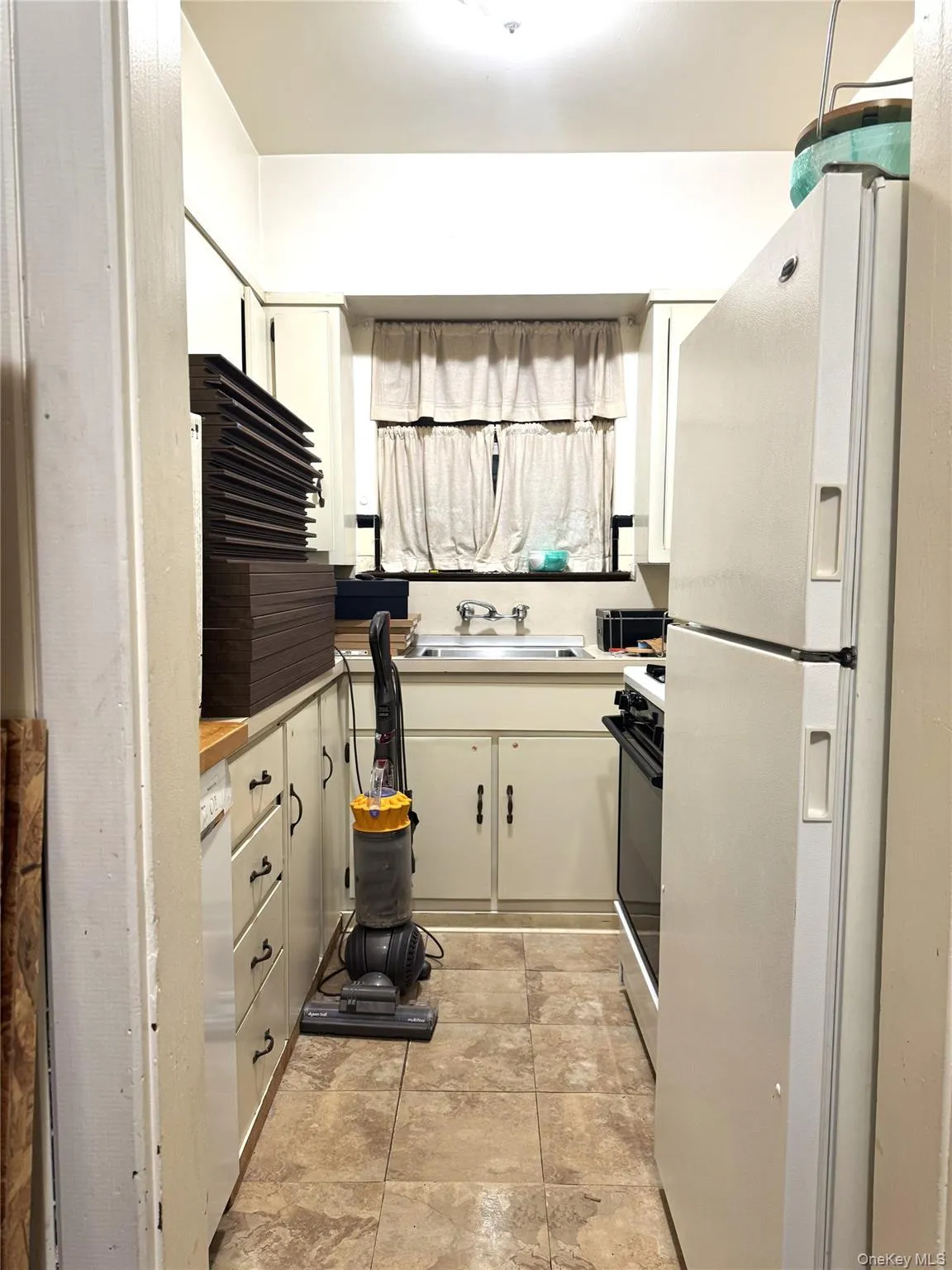 Kitchen with freestanding refrigerator, black stove, and light countertops Kitchen with freestanding refrigerator, black stove, and light countertops