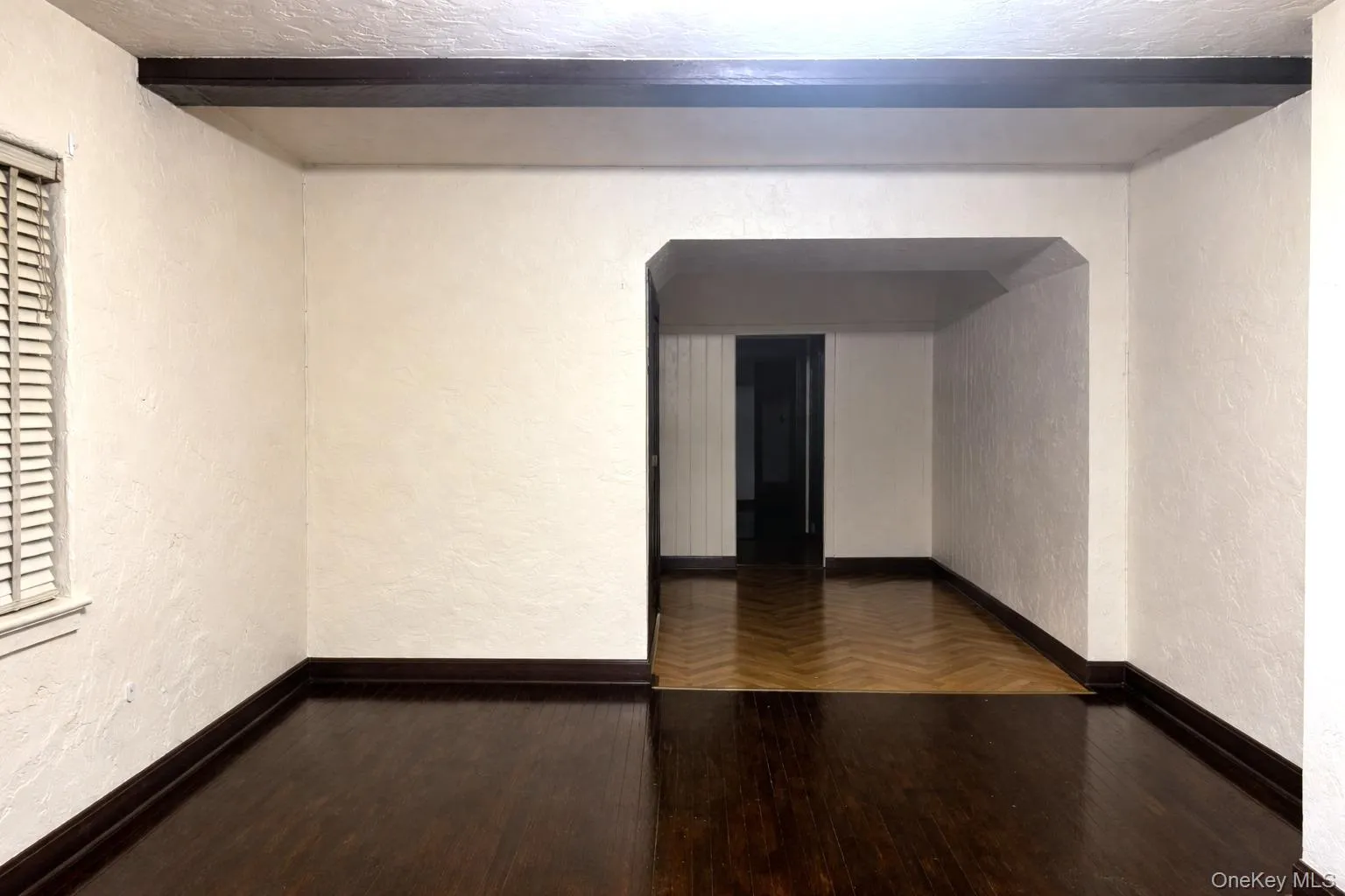 Spare room with a textured wall, hardwood / wood-style flooring, and beam ceiling Spare room with a textured wall, hardwood / wood-style flooring, and beam ceiling