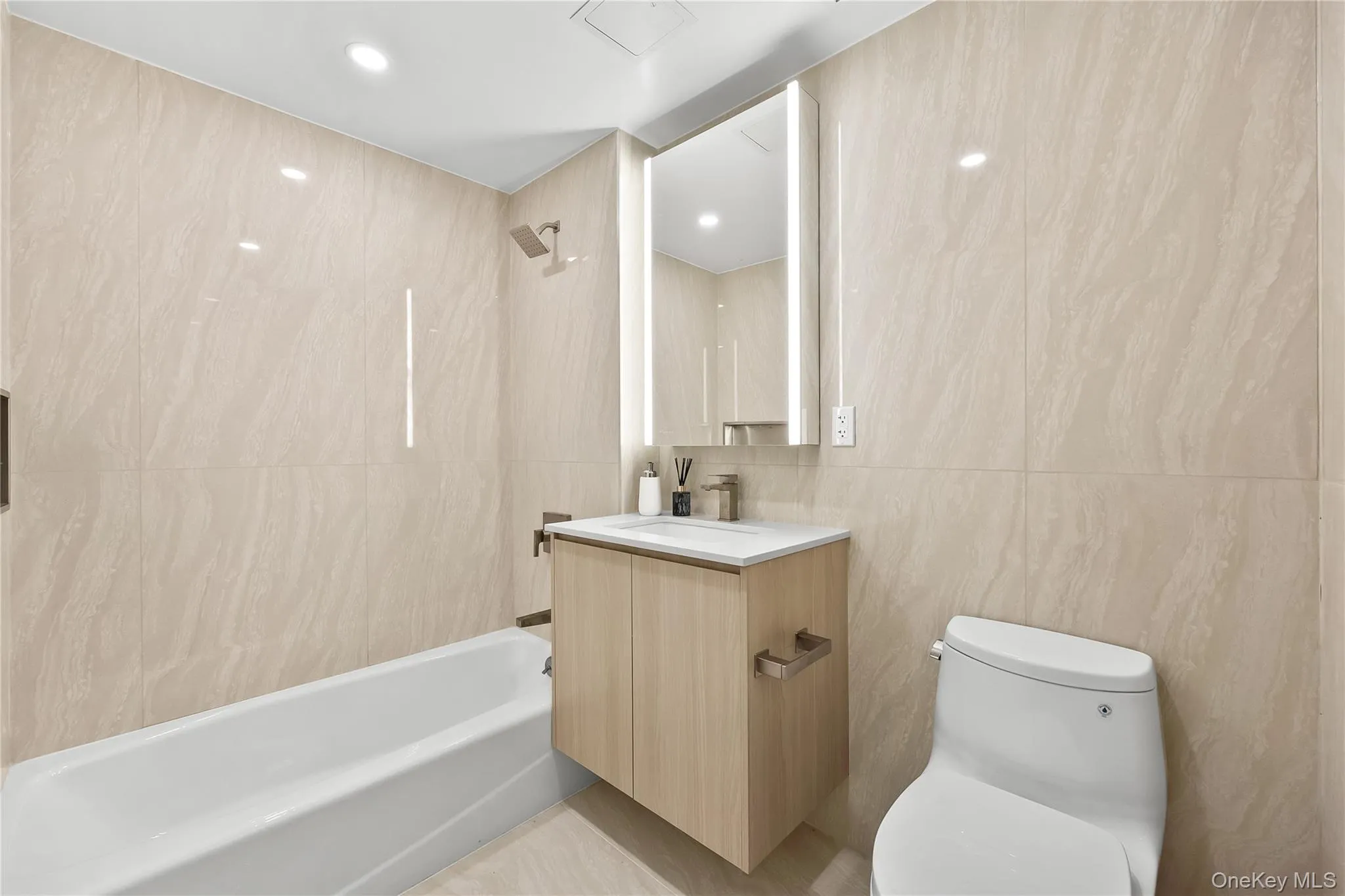 Full bath featuring vanity, shower / bath combination, tile walls, and recessed lighting Full bath featuring vanity, shower / bath combination, tile walls, and recessed lighting