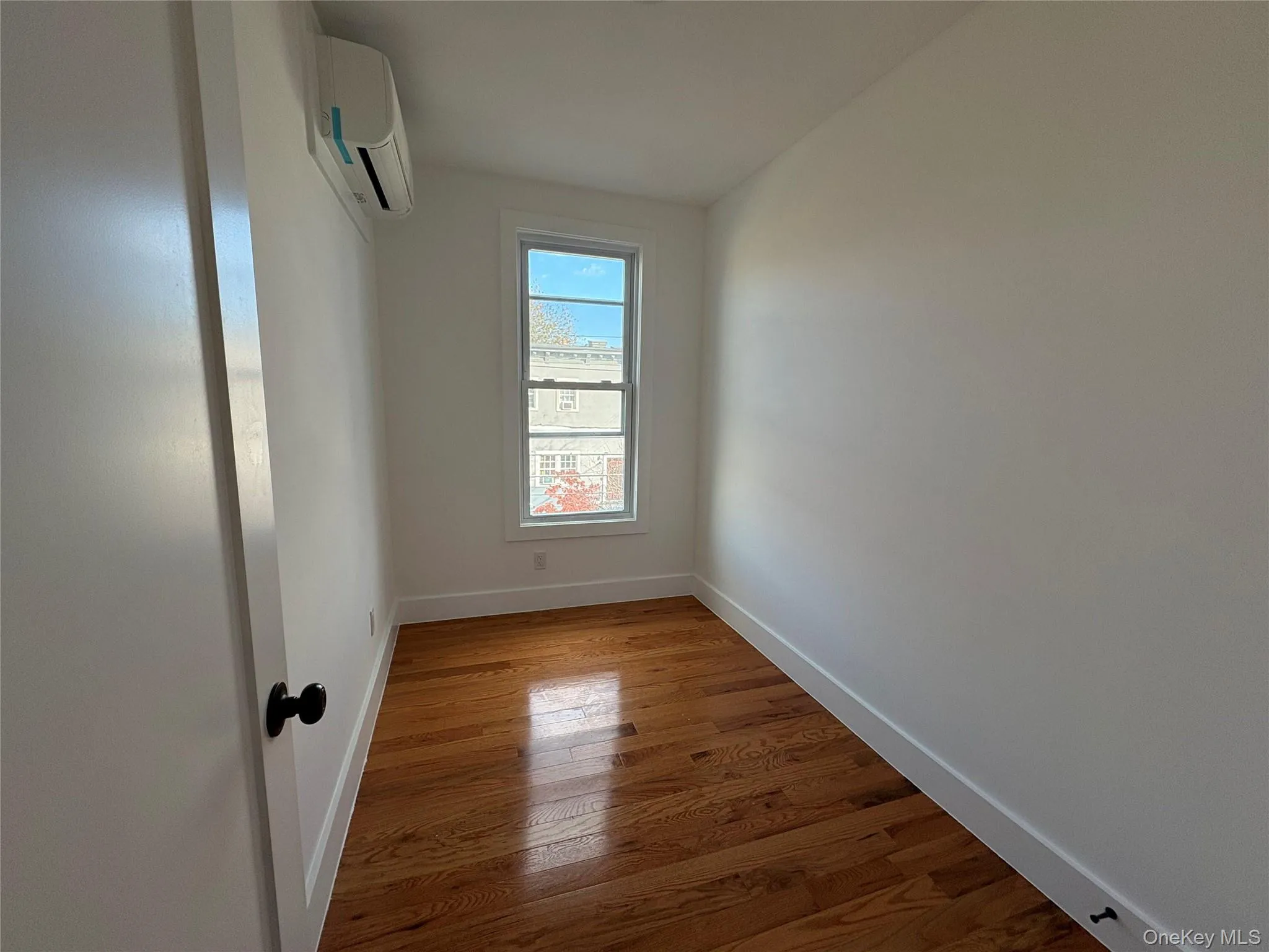 Spare room with light wood finished floors and an AC wall unit Spare room with light wood finished floors and an AC wall unit