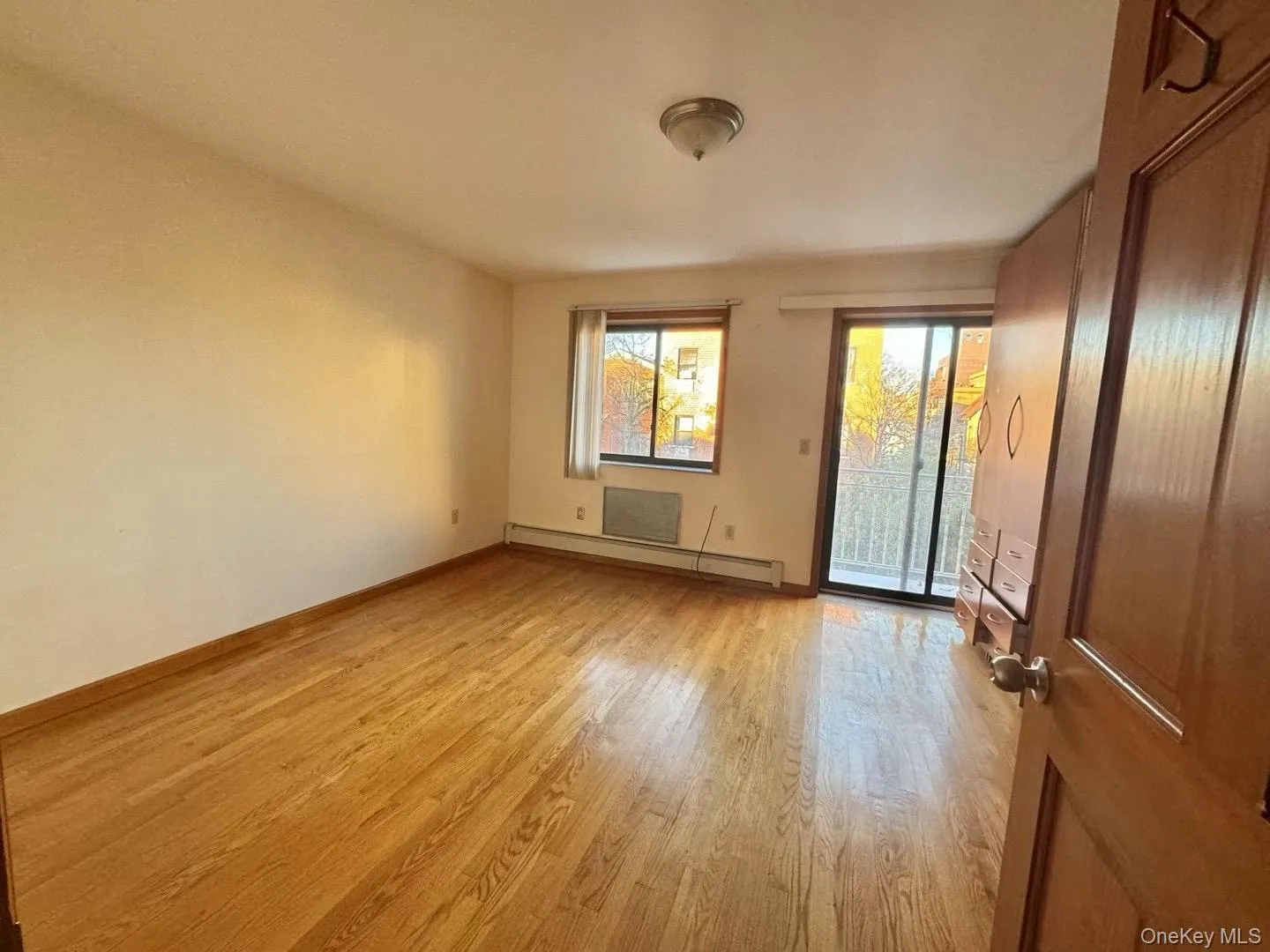 Unfurnished room featuring light wood-style floors and baseboard heating Unfurnished room featuring light wood-style floors and baseboard heating