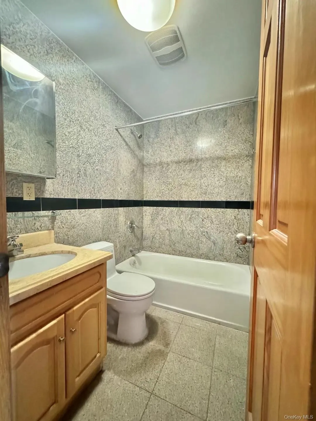 Full bathroom with tile walls, vanity, and shower / bathtub combination Full bathroom with tile walls, vanity, and shower / bathtub combination