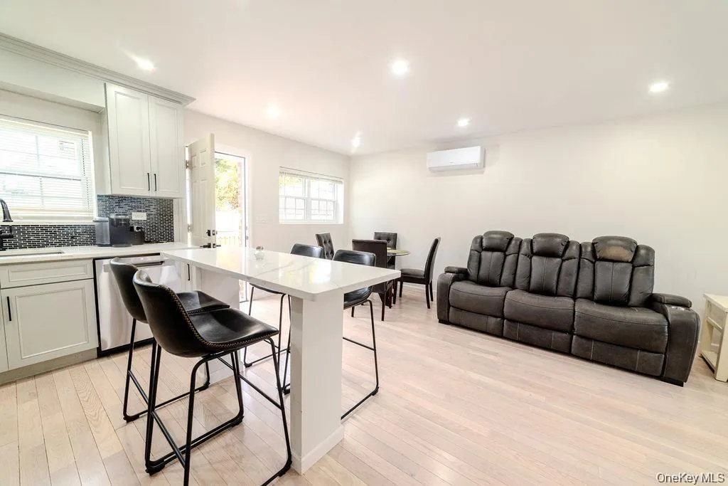 Kitchen with a breakfast bar area, decorative backsplash, stainless steel dishwasher, light wood finished floors, and open floor plan Kitchen with a breakfast bar area, decorative backsplash, stainless steel dishwasher, light wood finished floors, and open floor plan