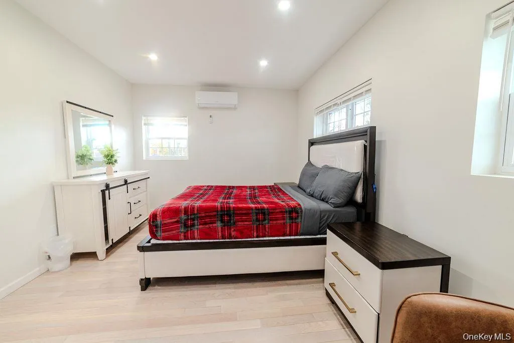 Bedroom featuring light wood-style floors, a wall unit AC, and recessed lighting Bedroom featuring light wood-style floors, a wall unit AC, and recessed lighting