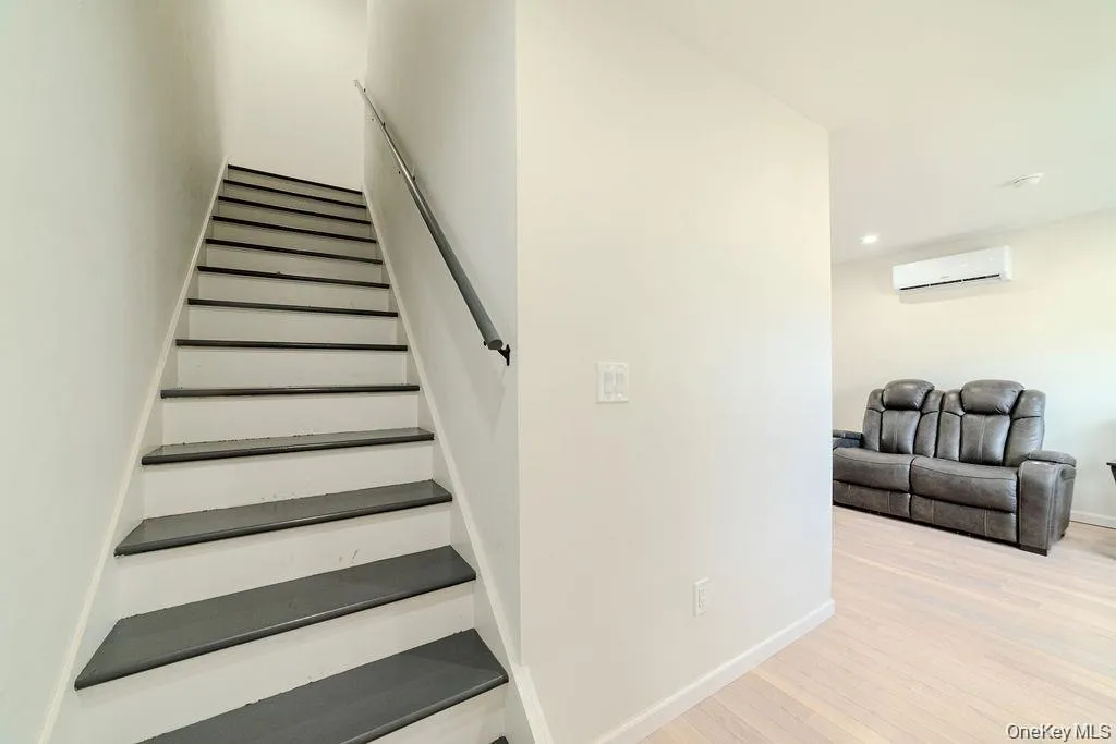 Staircase with wood finished floors and a wall mounted AC Staircase with wood finished floors and a wall mounted AC