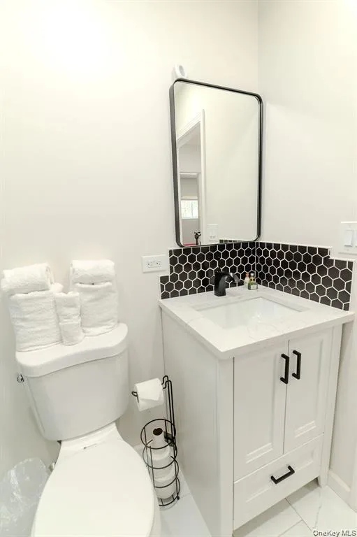 Half bathroom featuring vanity and backsplash Half bathroom featuring vanity and backsplash