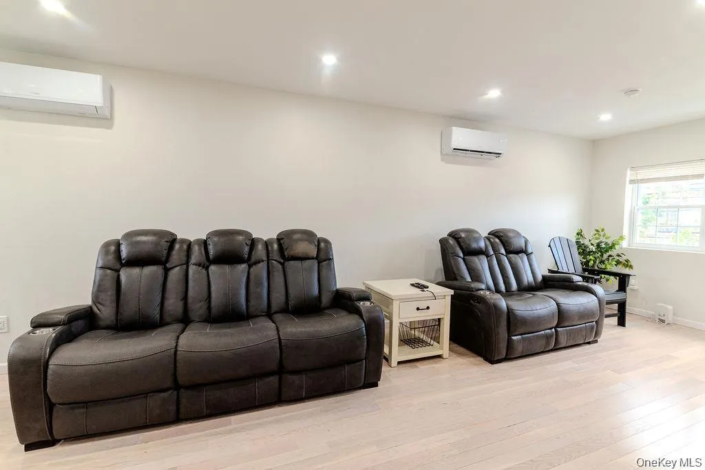Home theater room featuring an AC wall unit, recessed lighting, and light wood finished floors Home theater room featuring an AC wall unit, recessed lighting, and light wood finished floors