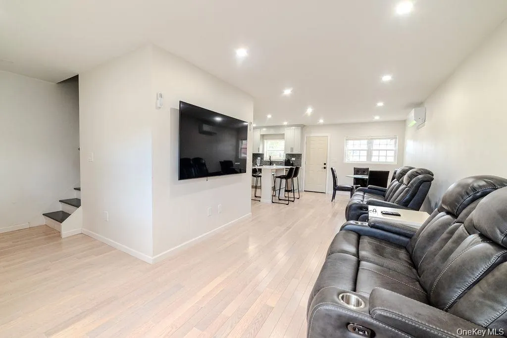 Living area featuring light wood-style flooring, stairway, recessed lighting, and an AC wall unit Living area featuring light wood-style flooring, stairway, recessed lighting, and an AC wall unit