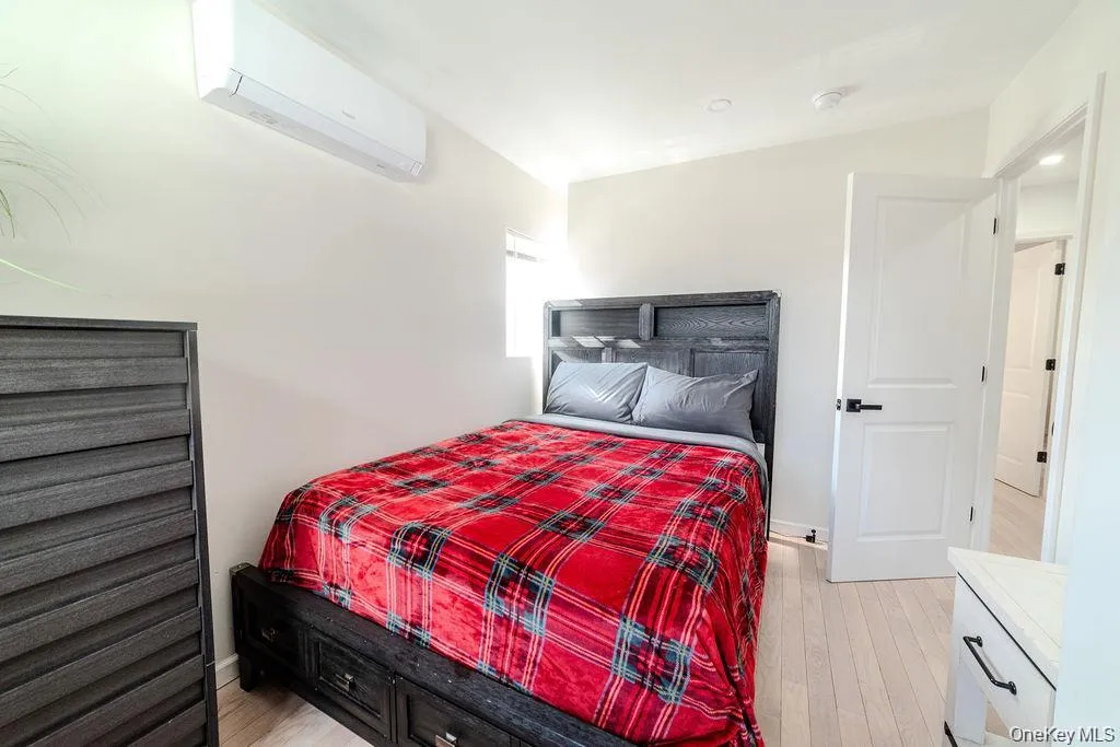 Bedroom with a wall unit AC and light wood finished floors Bedroom with a wall unit AC and light wood finished floors