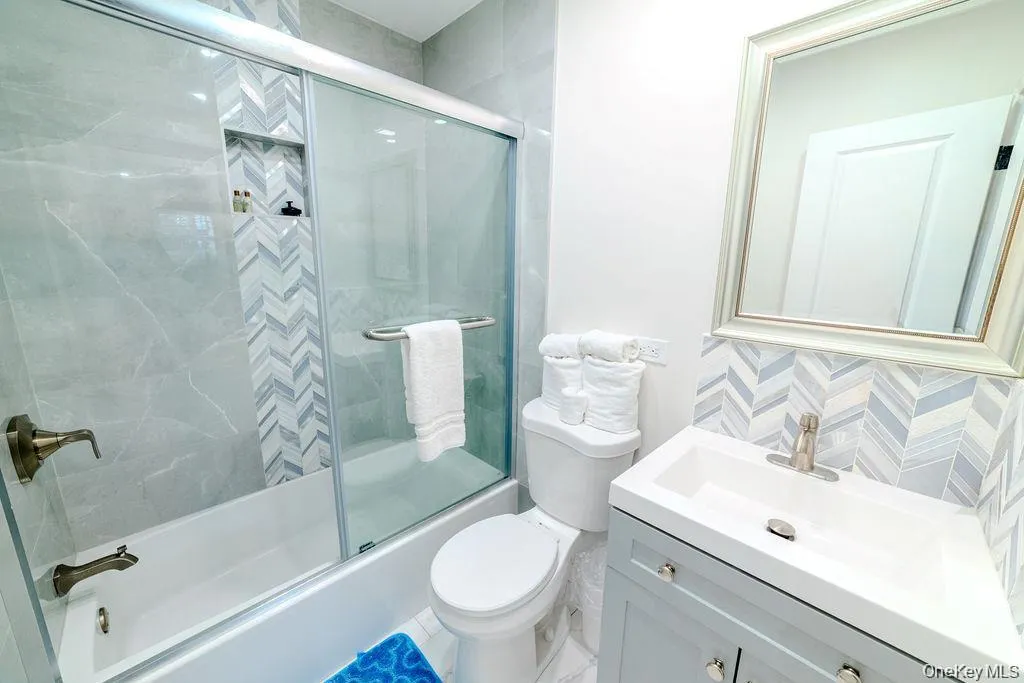 Full bath with enclosed tub / shower combo, vanity, and decorative backsplash Full bath with enclosed tub / shower combo, vanity, and decorative backsplash