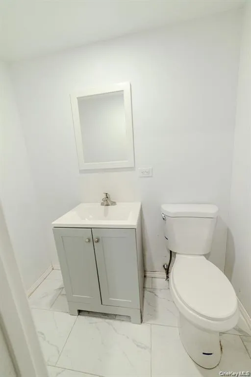Half bathroom with light marble finish flooring and vanity Half bathroom with light marble finish flooring and vanity