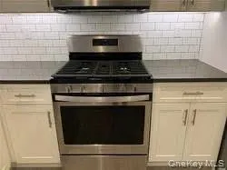 Kitchen featuring gas range, tasteful backsplash, and dark countertops Kitchen featuring gas range, tasteful backsplash, and dark countertops
