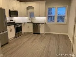 Kitchen with appliances with stainless steel finishes, dark countertops, light wood-type flooring, and white cabinetry Kitchen with appliances with stainless steel finishes, dark countertops, light wood-type flooring, and white cabinetry
