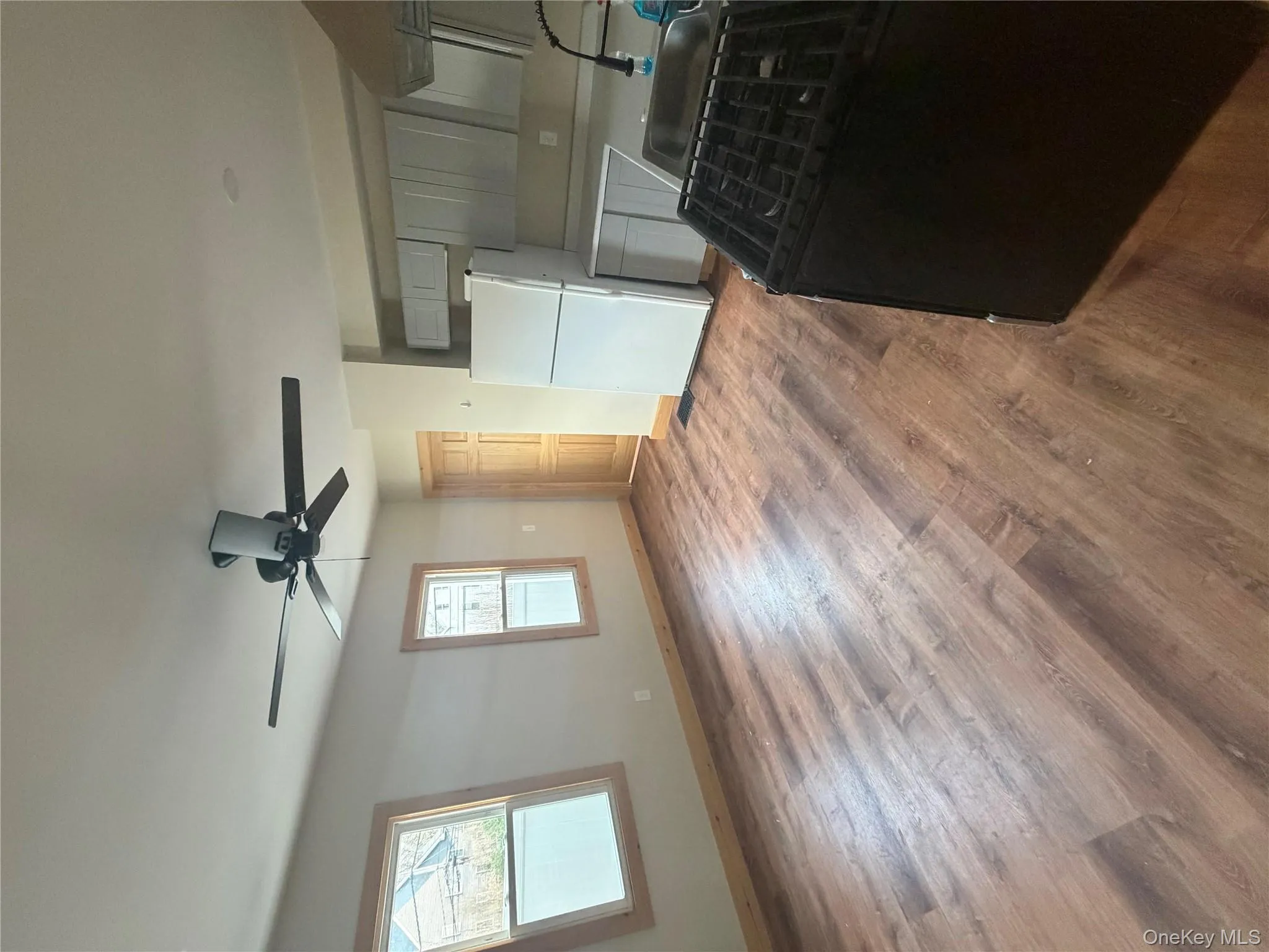 Kitchen with stove, fridge, light countertops, dark wood-style flooring, and a ceiling fan Kitchen with stove, fridge, light countertops, dark wood-style flooring, and a ceiling fan