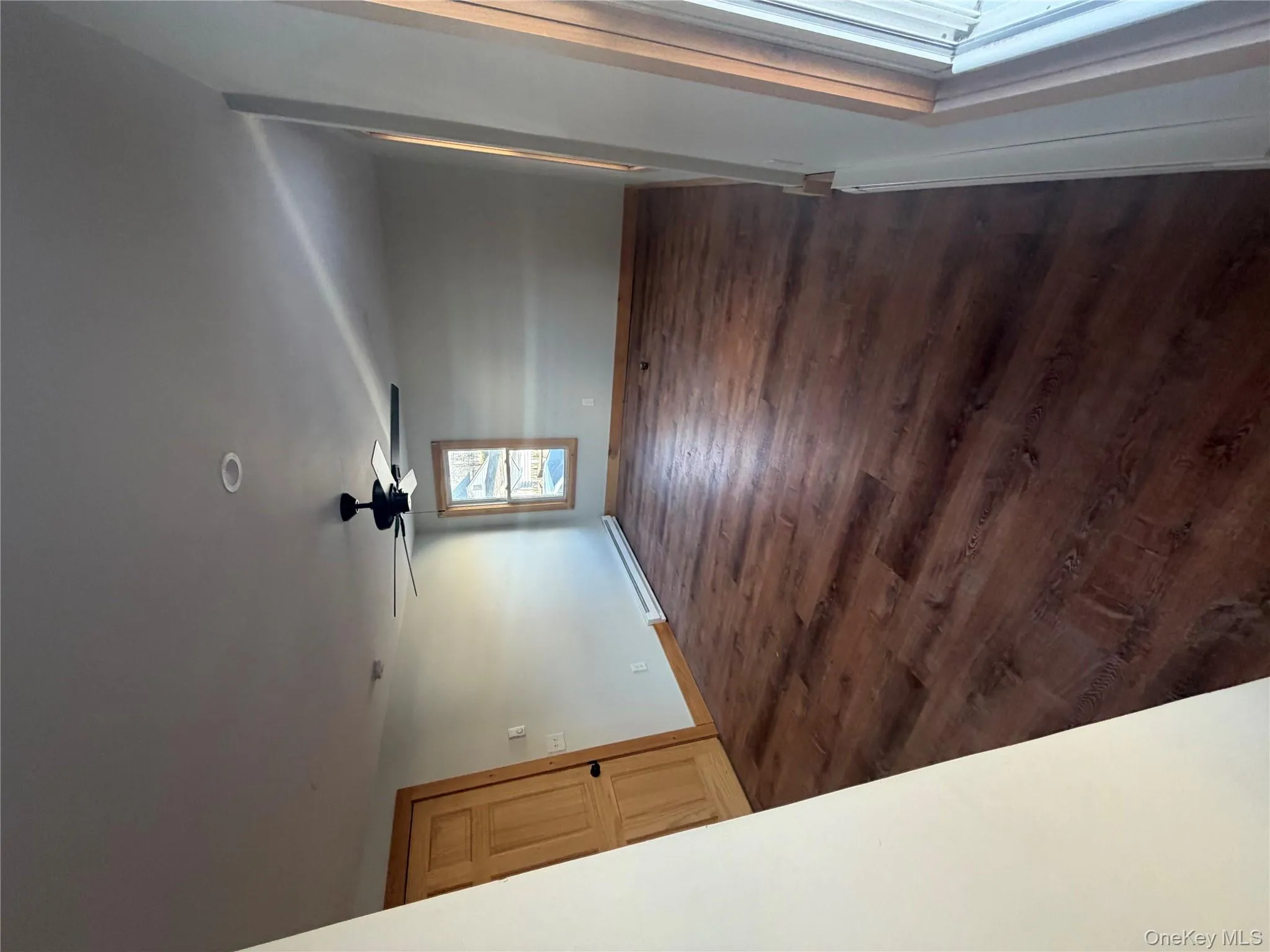 Empty room with baseboard heating, dark wood finished floors, and ceiling fan Empty room with baseboard heating, dark wood finished floors, and ceiling fan