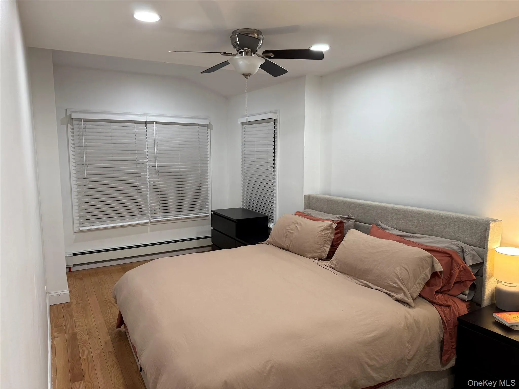 Bedroom featuring baseboard heating, wood finished floors, recessed lighting, a ceiling fan, and lofted ceiling Bedroom featuring baseboard heating, wood finished floors, recessed lighting, a ceiling fan, and lofted ceiling