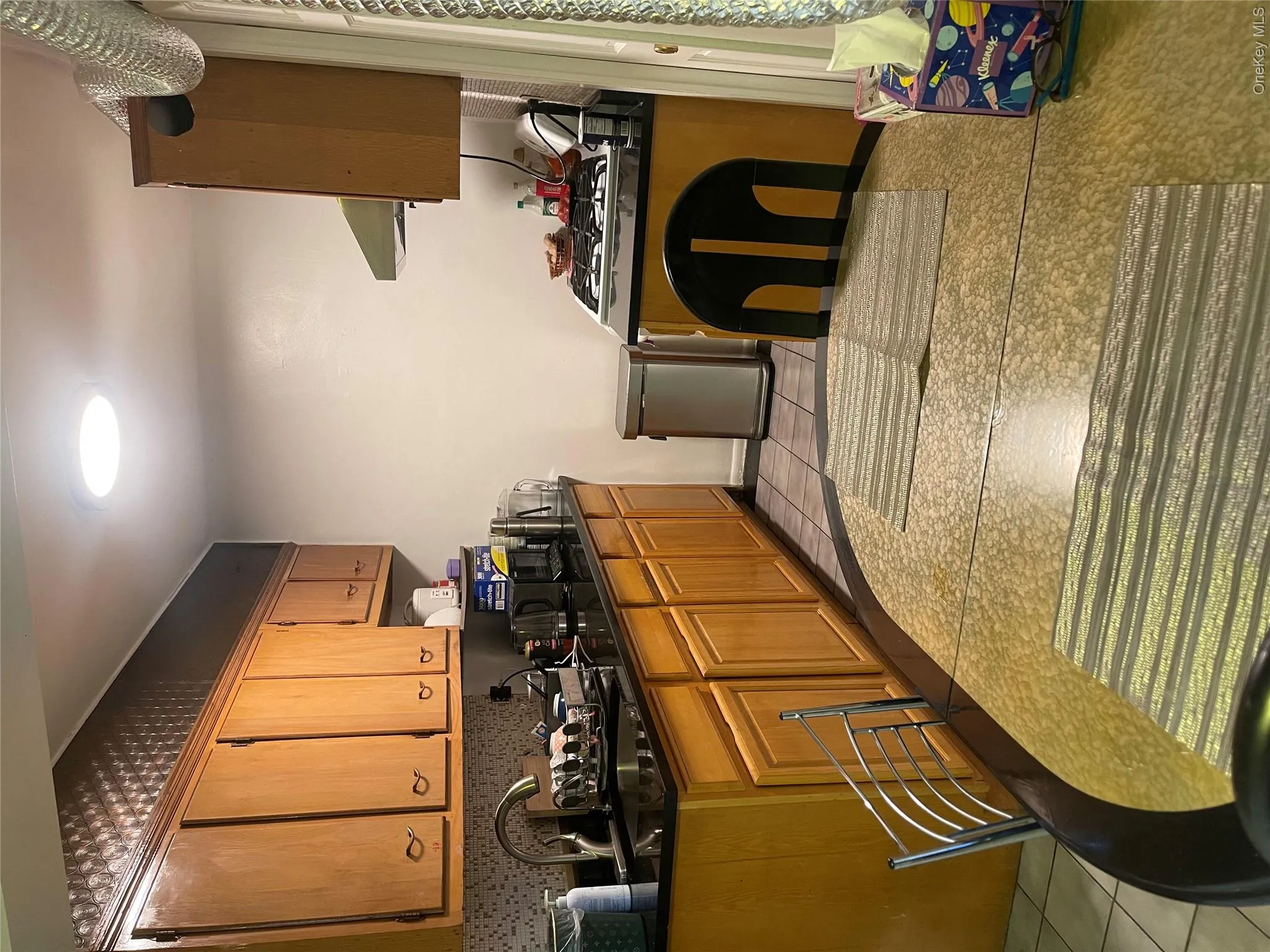 Kitchen featuring brown cabinetry, dark stone countertops, light tile patterned floors, extractor fan, and stove Kitchen featuring brown cabinetry, dark stone countertops, light tile patterned floors, extractor fan, and stove