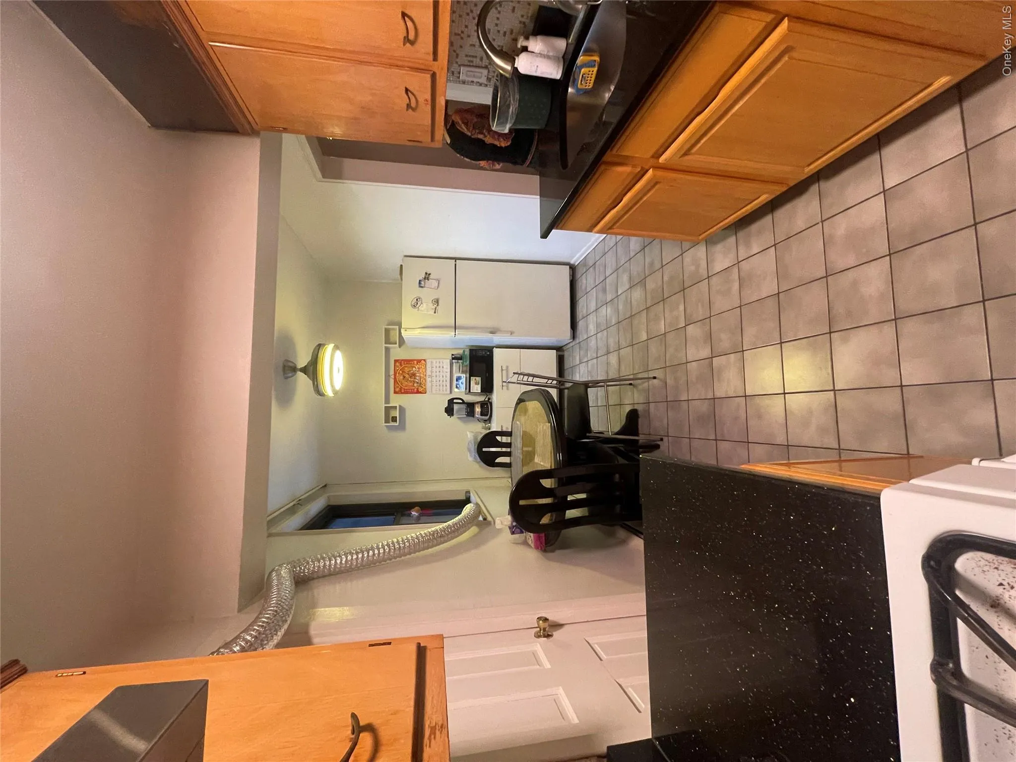 Kitchen with fridge, light tile patterned floors, brown cabinetry, dark stone counters, and range Kitchen with fridge, light tile patterned floors, brown cabinetry, dark stone counters, and range