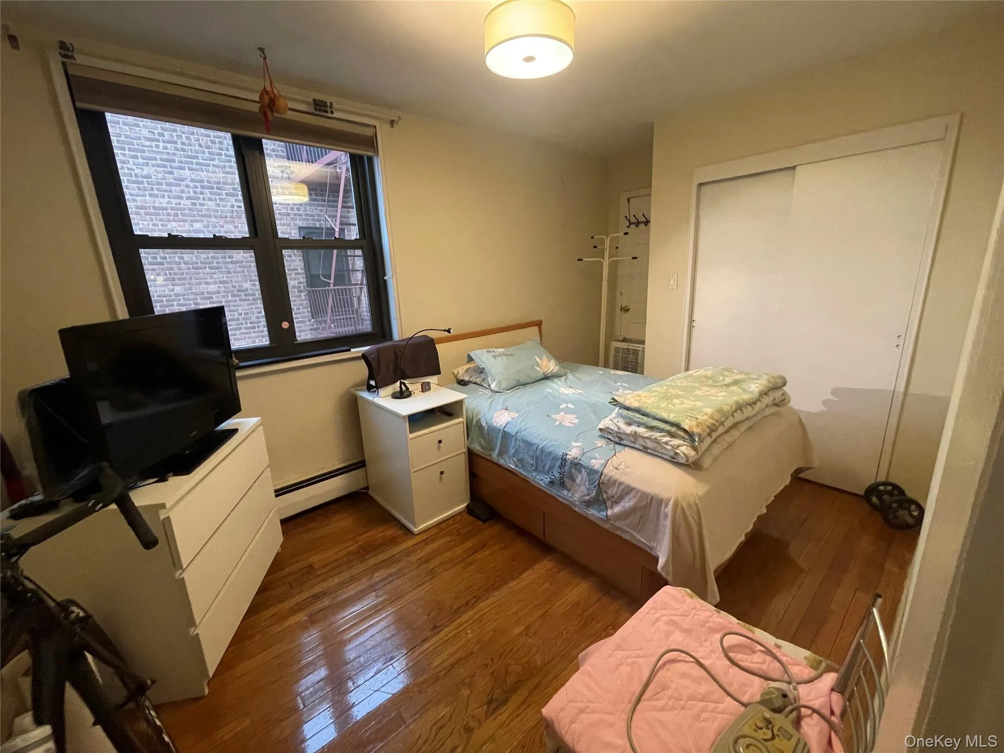 Bedroom featuring hardwood / wood-style floors, a baseboard heating unit, and a closet Bedroom featuring hardwood / wood-style floors, a baseboard heating unit, and a closet