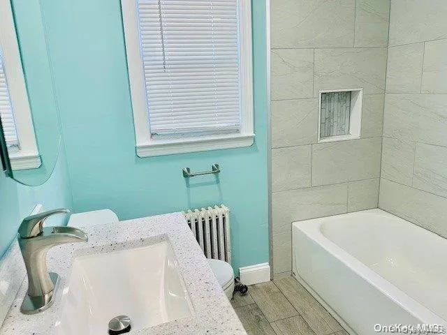 Bathroom featuring vanity, radiator heating unit, and shower / washtub combination Bathroom featuring vanity, radiator heating unit, and shower / washtub combination