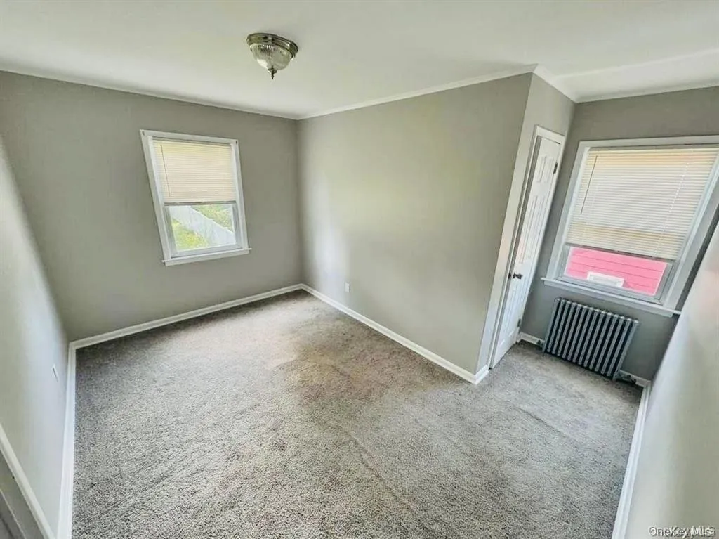 Unfurnished room with radiator, carpet, and ornamental molding Unfurnished room with radiator, carpet, and ornamental molding