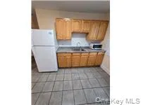 Kitchen featuring freestanding refrigerator, brown cabinetry, and light tile patterned floors Kitchen featuring freestanding refrigerator, brown cabinetry, and light tile patterned floors
