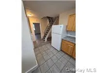 Kitchen featuring brown cabinetry, freestanding refrigerator, and light tile patterned floors Kitchen featuring brown cabinetry, freestanding refrigerator, and light tile patterned floors