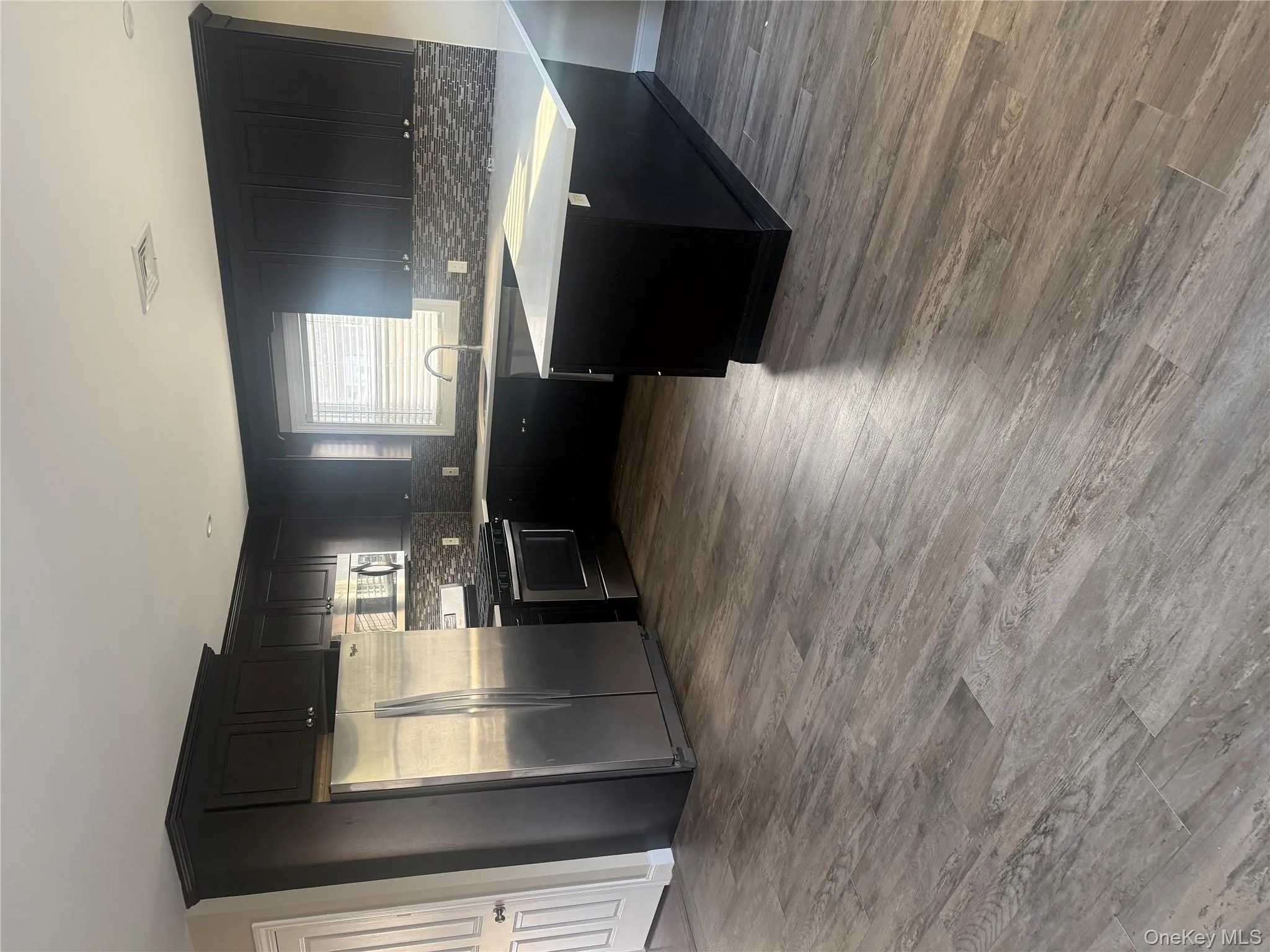 Kitchen with dark cabinets, refrigerator, stove, a peninsula, and dark wood-style flooring Kitchen with dark cabinets, refrigerator, stove, a peninsula, and dark wood-style flooring