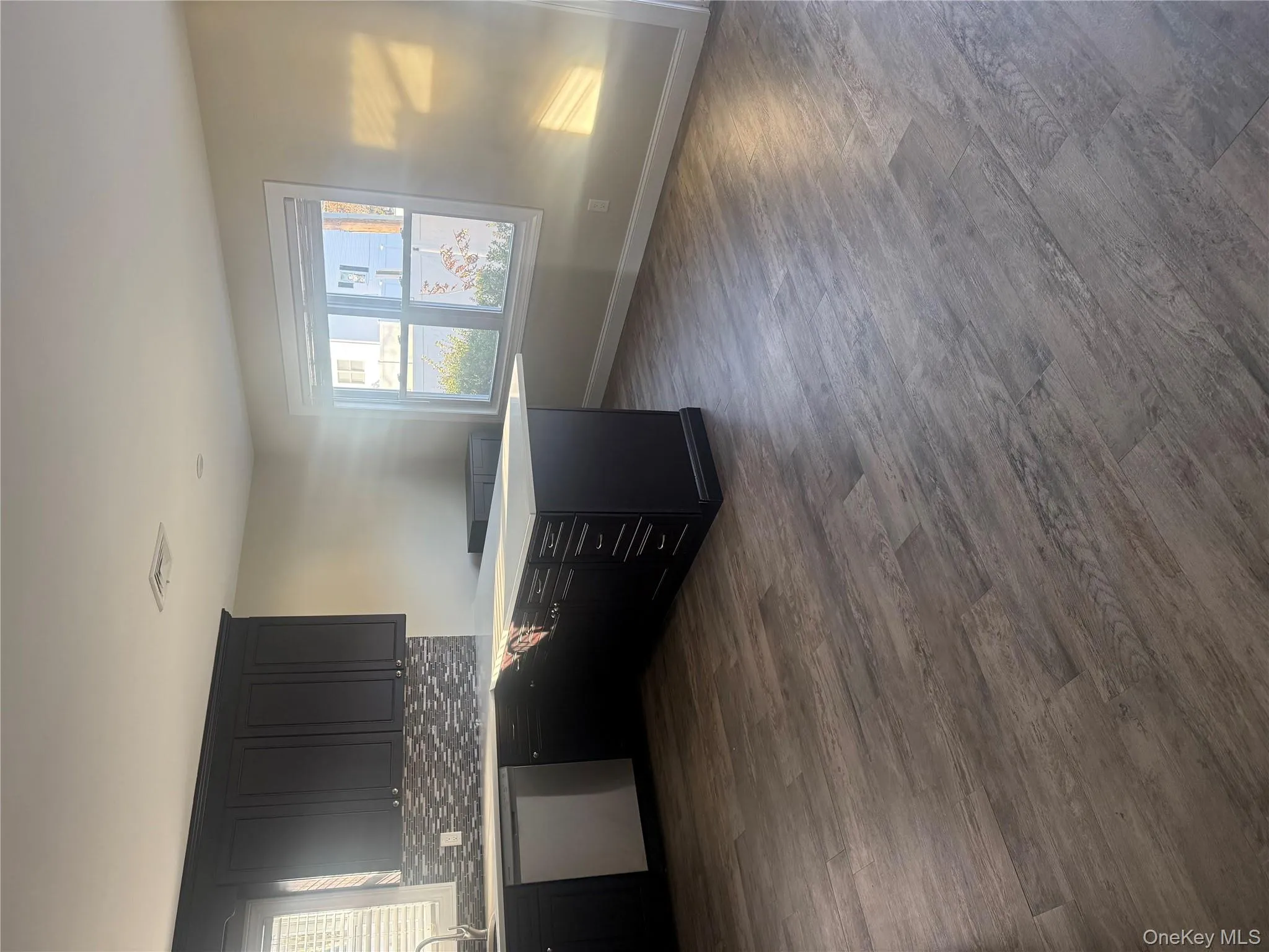 Kitchen featuring a peninsula, dark cabinetry, dishwashing machine, decorative backsplash, and dark wood finished floors Kitchen featuring a peninsula, dark cabinetry, dishwashing machine, decorative backsplash, and dark wood finished floors