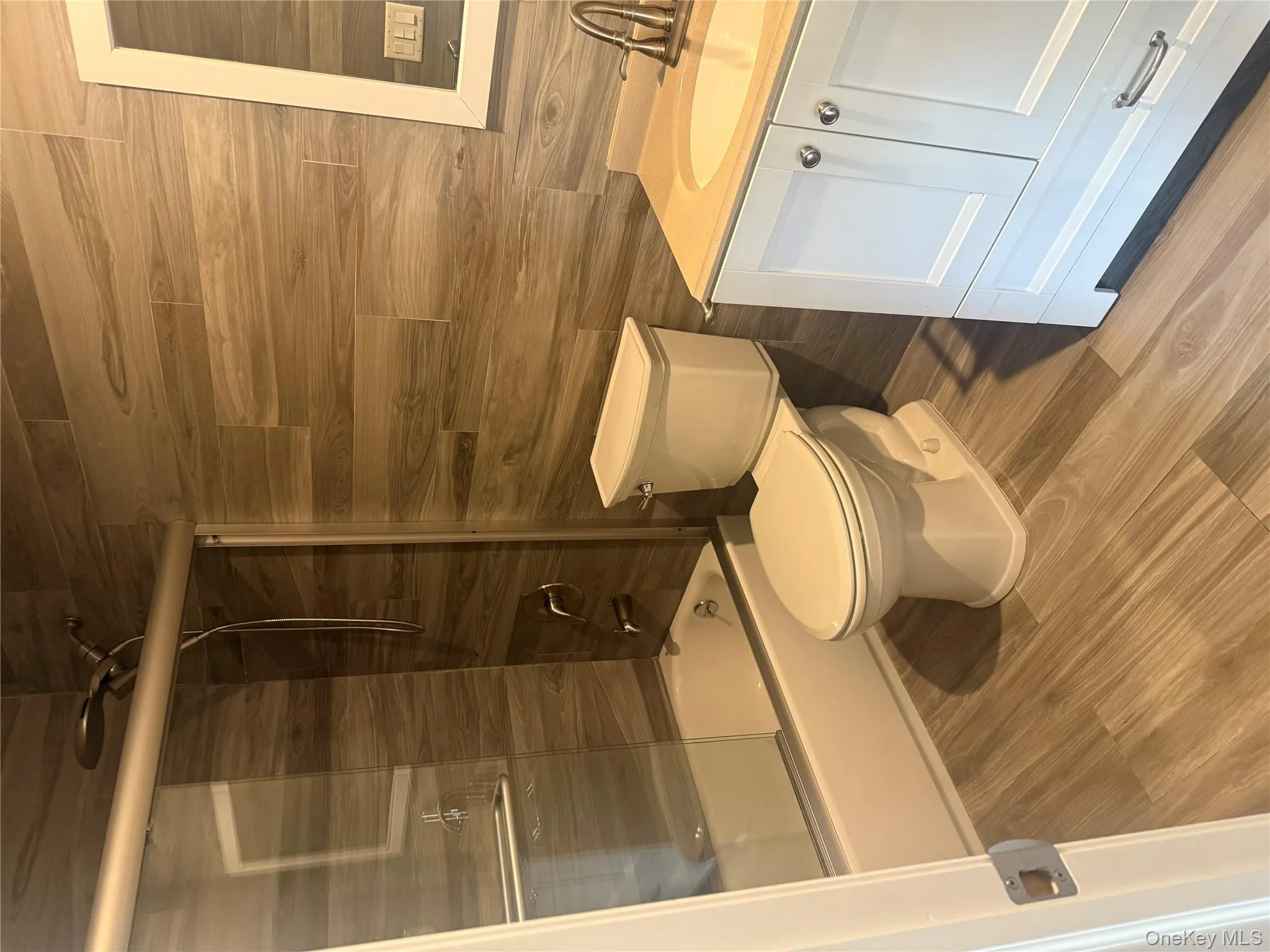 Full bathroom featuring vanity, bath / shower combo with glass door, and light wood-type flooring Full bathroom featuring vanity, bath / shower combo with glass door, and light wood-type flooring