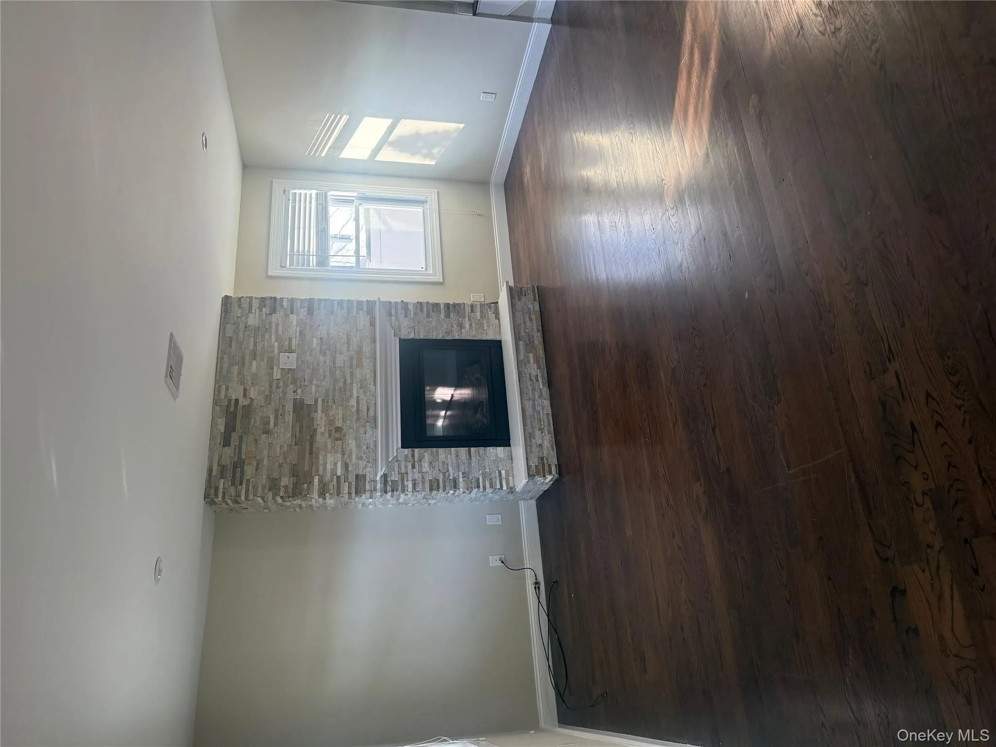 Unfurnished living room with a fireplace and dark wood-type flooring Unfurnished living room with a fireplace and dark wood-type flooring