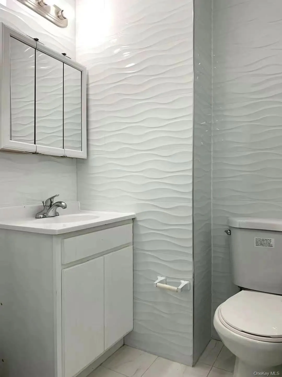 Half bathroom featuring vanity, tile walls, and light marble finish floors Half bathroom featuring vanity, tile walls, and light marble finish floors