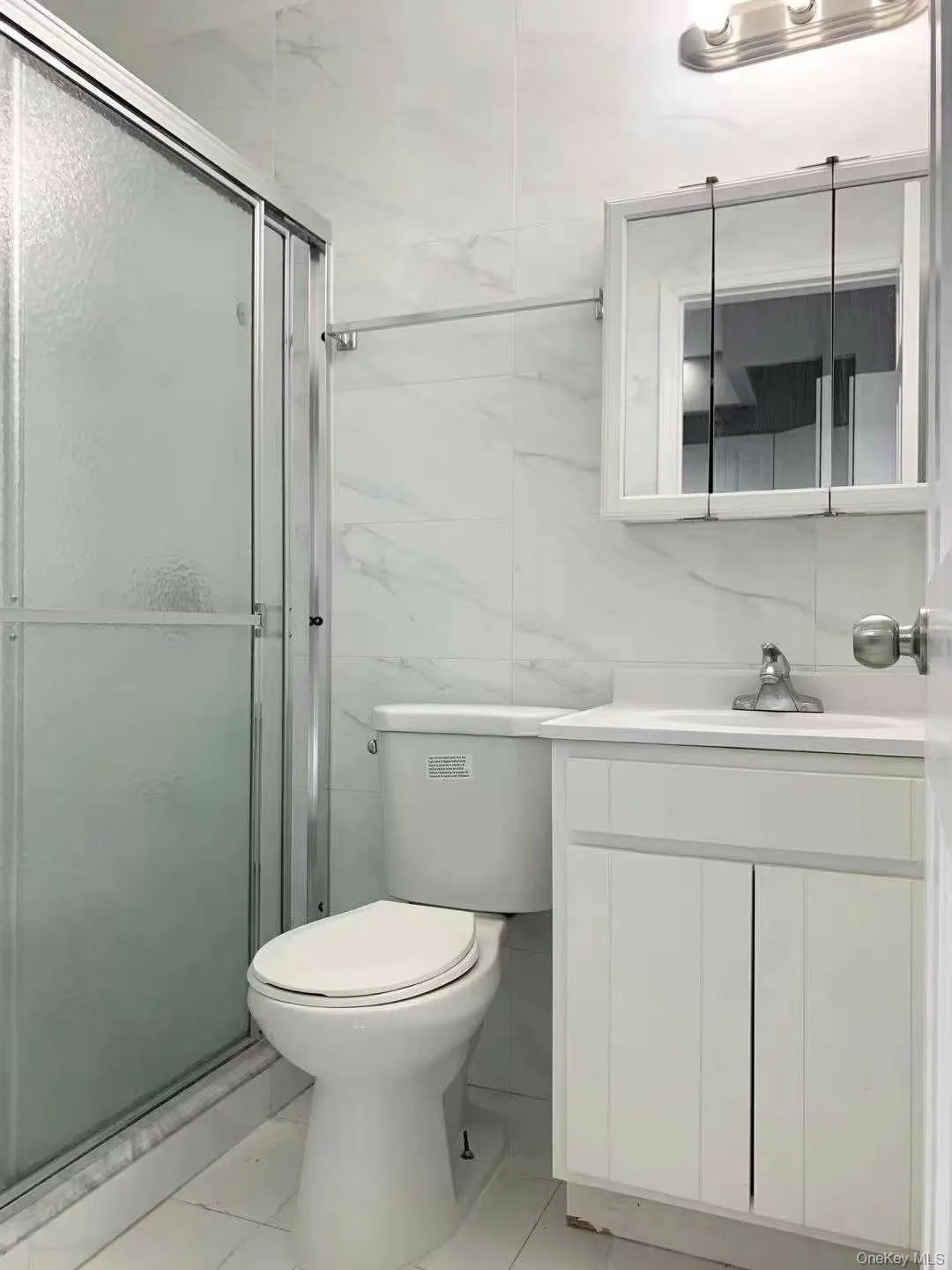 Bathroom with tile walls, a shower stall, vanity, and decorative backsplash Bathroom with tile walls, a shower stall, vanity, and decorative backsplash