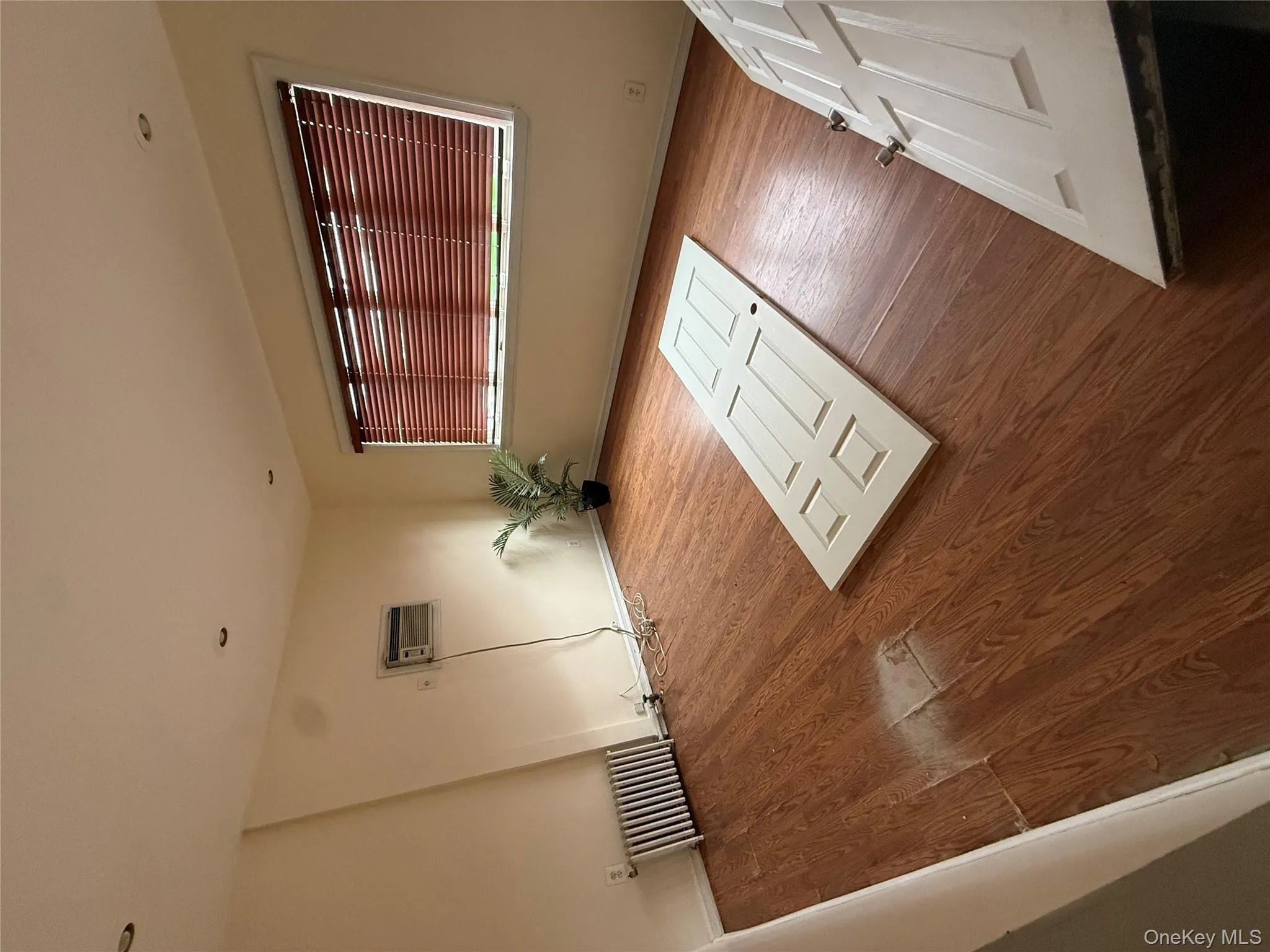 Empty room with wood finished floors, radiator heating unit, and a wall unit AC Empty room with wood finished floors, radiator heating unit, and a wall unit AC