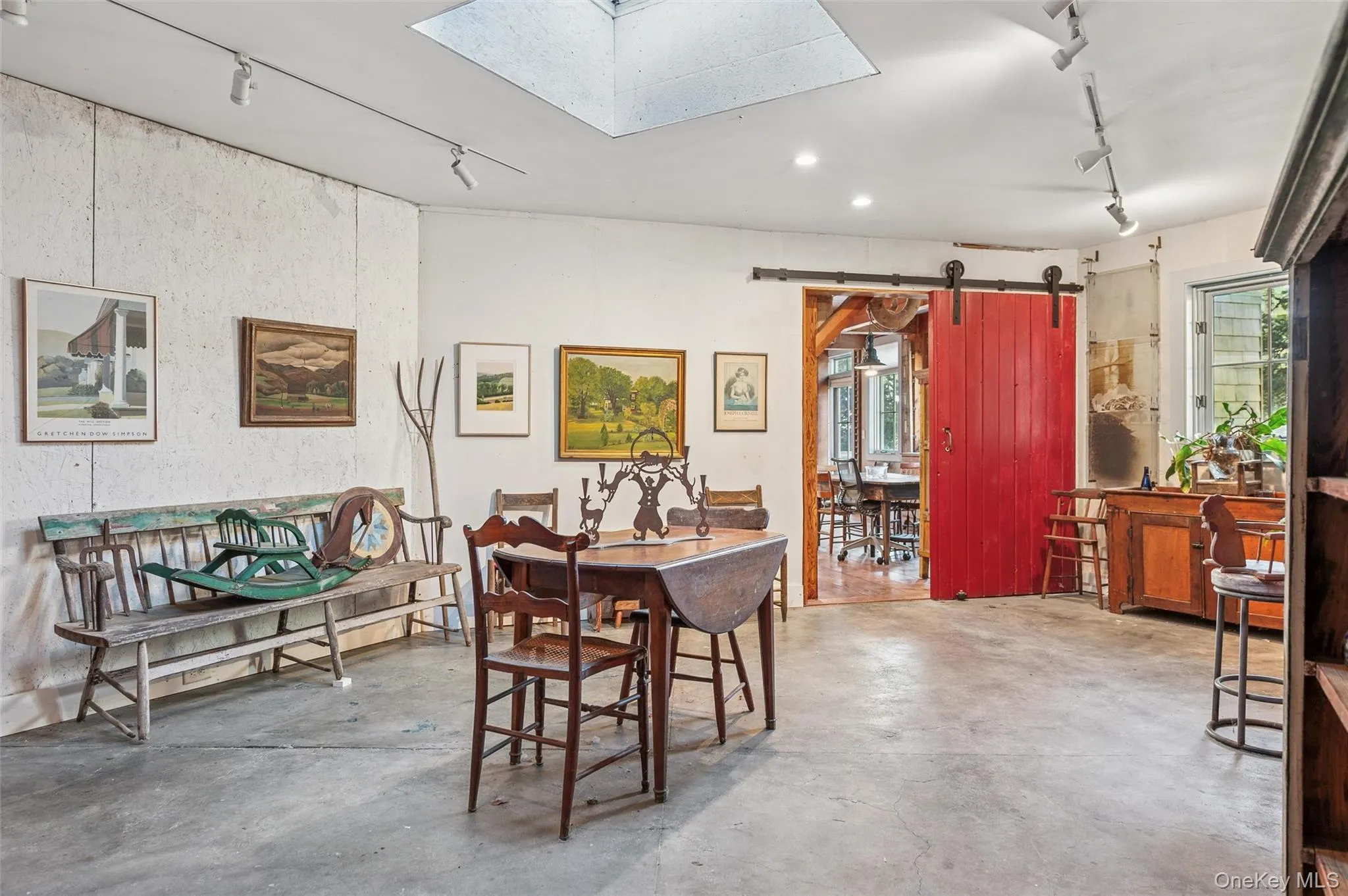 Dining room with rail lighting, a barn door, a skylight, and concrete flooring Dining room with rail lighting, a barn door, a skylight, and concrete flooring