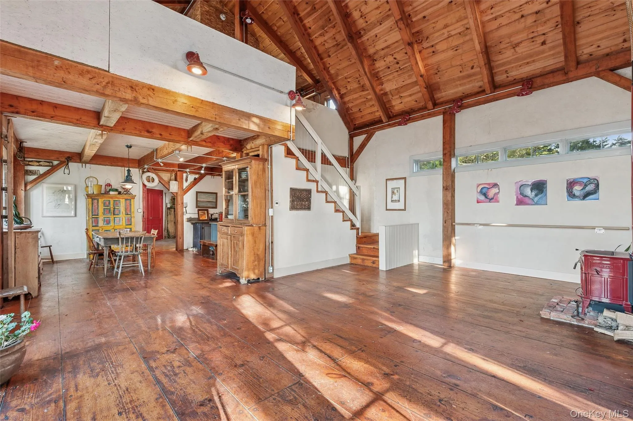 Unfurnished living room with a wood ceiling with exposed beams, dark wood-type flooring, stairway, and high vaulted ceiling Unfurnished living room with a wood ceiling with exposed beams, dark wood-type flooring, stairway, and high vaulted ceiling