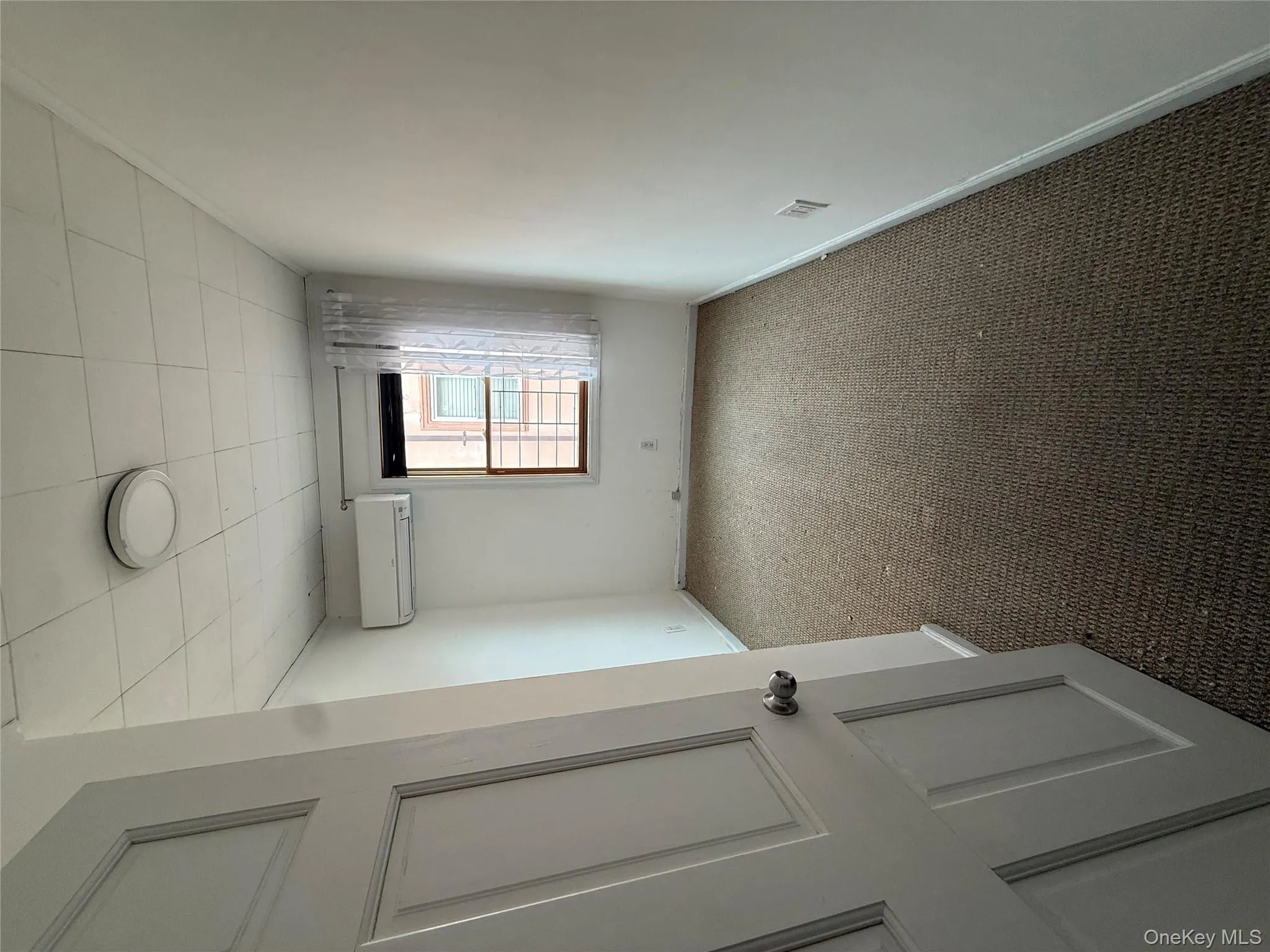 Empty room with carpet flooring and an AC wall unit Empty room with carpet flooring and an AC wall unit