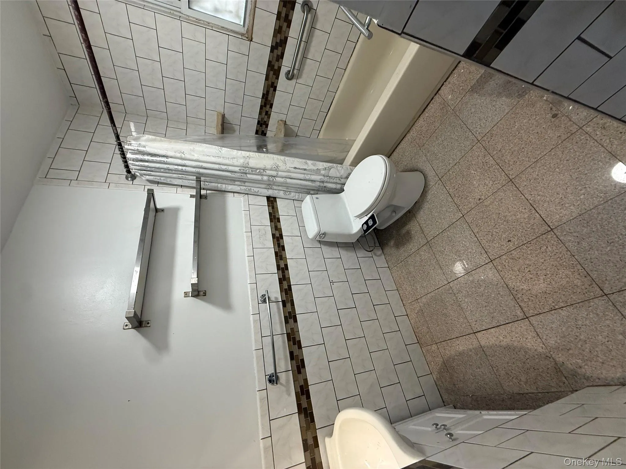 Bathroom with tile walls, vanity, wainscoting, and shower / bathtub combination with curtain Bathroom with tile walls, vanity, wainscoting, and shower / bathtub combination with curtain