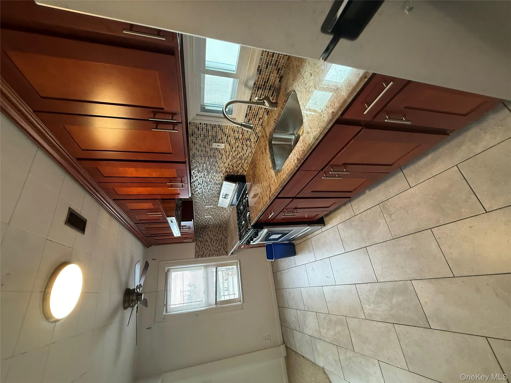 Kitchen featuring stainless steel gas range, light stone countertops, ceiling fan, refrigerator, and light tile patterned floors Kitchen featuring stainless steel gas range, light stone countertops, ceiling fan, refrigerator, and light tile patterned floors