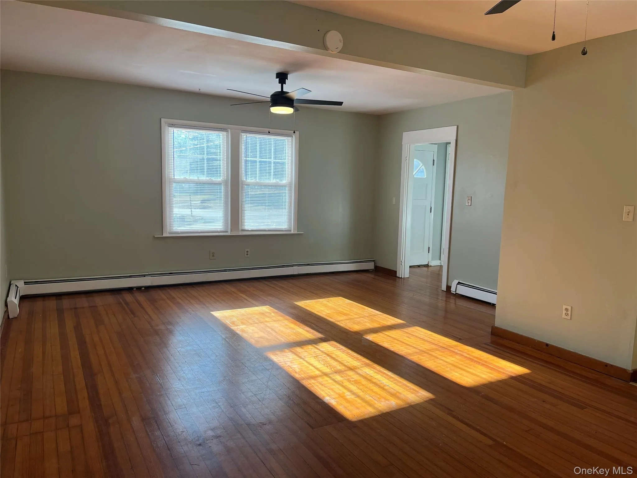 Spare room featuring a ceiling fan, a baseboard radiator, and dark wood-style floors Spare room featuring a ceiling fan, a baseboard radiator, and dark wood-style floors