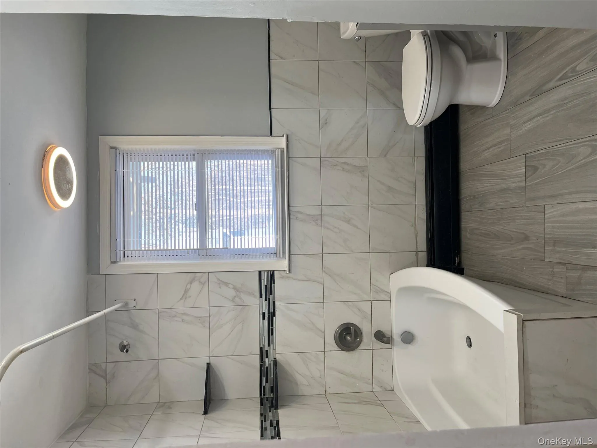 Bathroom with tile walls, shower / bathtub combination, baseboard heating, and a wainscoted wall Bathroom with tile walls, shower / bathtub combination, baseboard heating, and a wainscoted wall